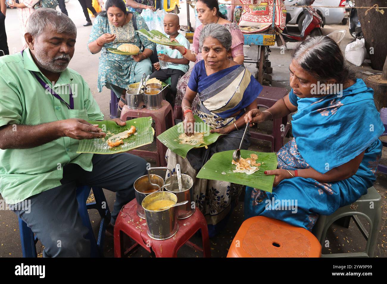 Die Leute essen Tiffin, benutzen ein Bananenblatt als Teller, in einem Street Food Stall in Tirupathi, an Stockfoto
