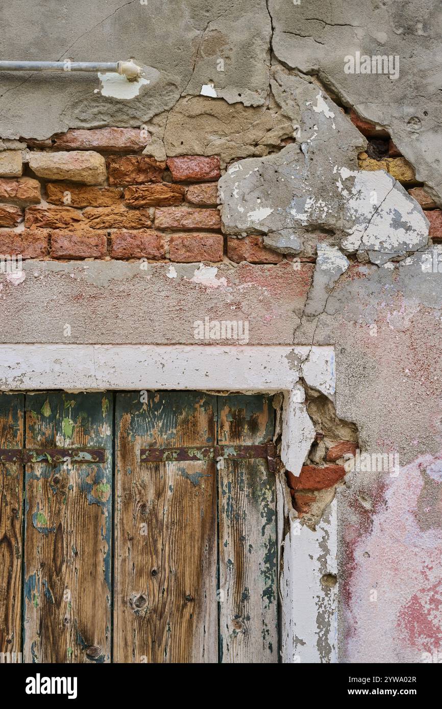 Alte zerbröckelnde Wand- und Fensterrahmen mit verwittertem Holz eines alten Rollladens, Burano, Venedig Italien Stockfoto