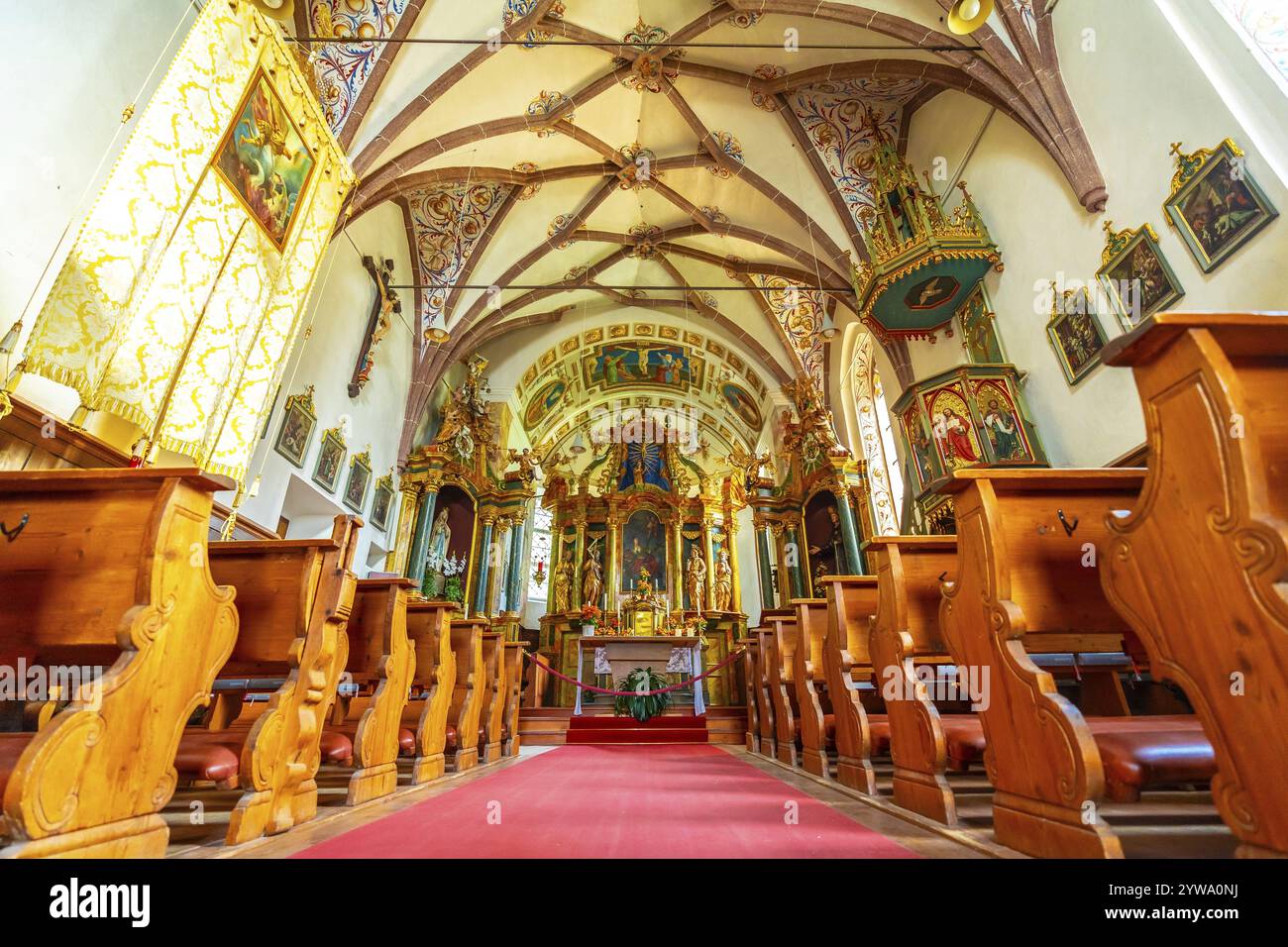 Innenraum der Kirche St. Magdalena im val di funes, mit Fresken, Bänken und rotem Teppich, in den dolomiten, italien Stockfoto