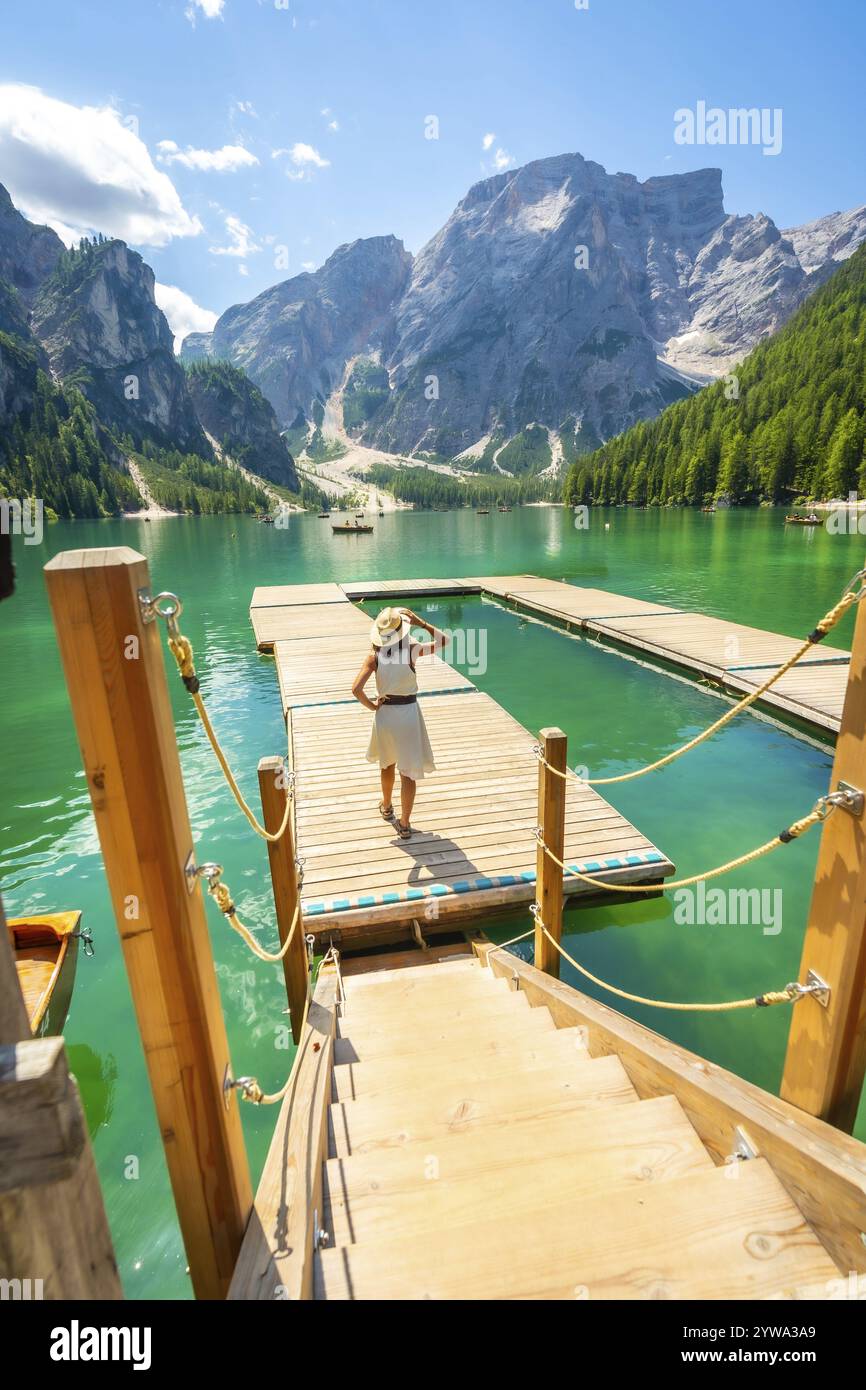 Touristen genießen einen atemberaubenden Blick auf den pragser See in den italienischen dolomiten, der auf einem hölzernen Pier mit smaragdgrünem Wasser und majestätischen Bergen steht Stockfoto