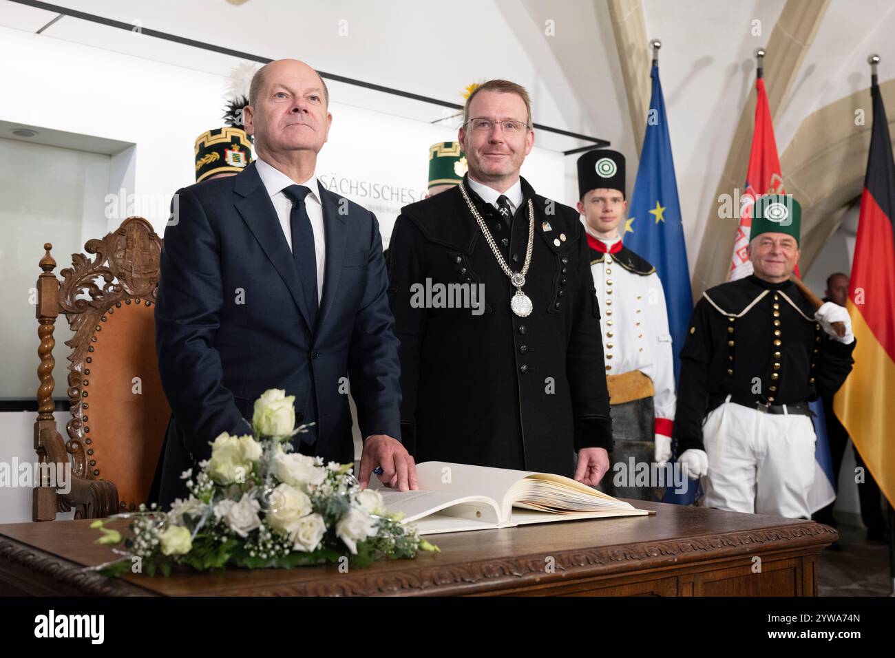 Freiberg, Deutschland. Dezember 2024. Bundeskanzler Olaf Scholz (SPD, l) unterschreibt das Goldene Buch der Stadt zusammen mit Sven Krüger, Bürgermeister von Freiberg, im Sächsischen Oberbergamt. Thema des Treffens im Erzgebirge ist die nachhaltige Lithiumgewinnung für Batterien für Elektroautos. Quelle: Sebastian Kahnert/dpa/Alamy Live News Stockfoto