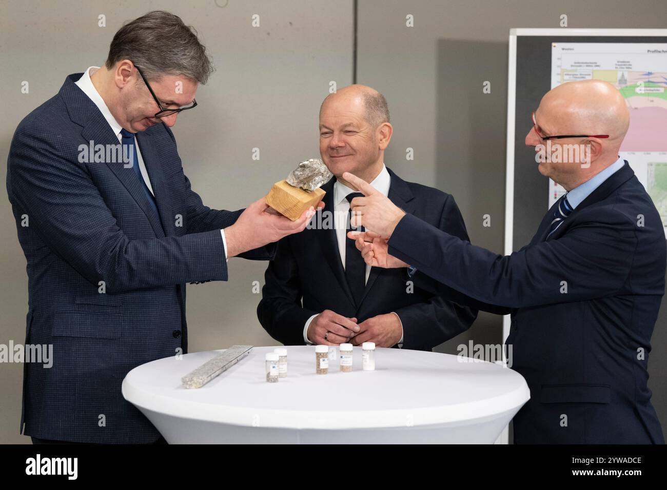 Freiberg, Deutschland. Dezember 2024. Bundeskanzler Olaf Scholz (SPD, Zentrum) und Aleksandar Vucic (links), Präsident Serbiens, untersuchen im Stadt- und Bergbaumuseum zusammen mit Marko Uhlig (rechts), Geschäftsführer von Zinnwald Lithium, ein lithiumhaltiges Gestein. Thema des Treffens im Erzgebirge ist die nachhaltige Lithiumgewinnung für Batterien für Elektroautos. Quelle: Sebastian Kahnert/dpa/Alamy Live News Stockfoto