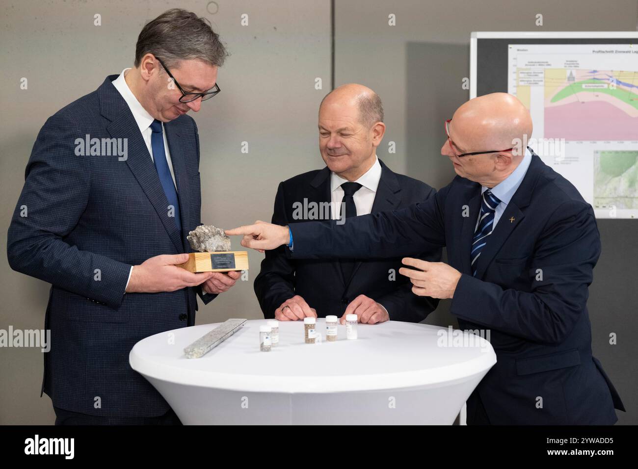 Freiberg, Deutschland. Dezember 2024. Bundeskanzler Olaf Scholz (SPD, Zentrum) und Aleksandar Vucic (links), Präsident Serbiens, untersuchen im Stadt- und Bergbaumuseum zusammen mit Marko Uhlig (rechts), Geschäftsführer von Zinnwald Lithium, ein lithiumhaltiges Gestein. Thema des Treffens im Erzgebirge ist die nachhaltige Lithiumgewinnung für Batterien für Elektroautos. Quelle: Sebastian Kahnert/dpa/Alamy Live News Stockfoto