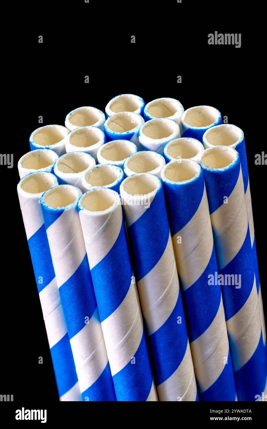 Ein Bündel blauer und weißer Trinkhalme aus Papier, fotografiert auf schwarzem Hintergrund Stockfoto