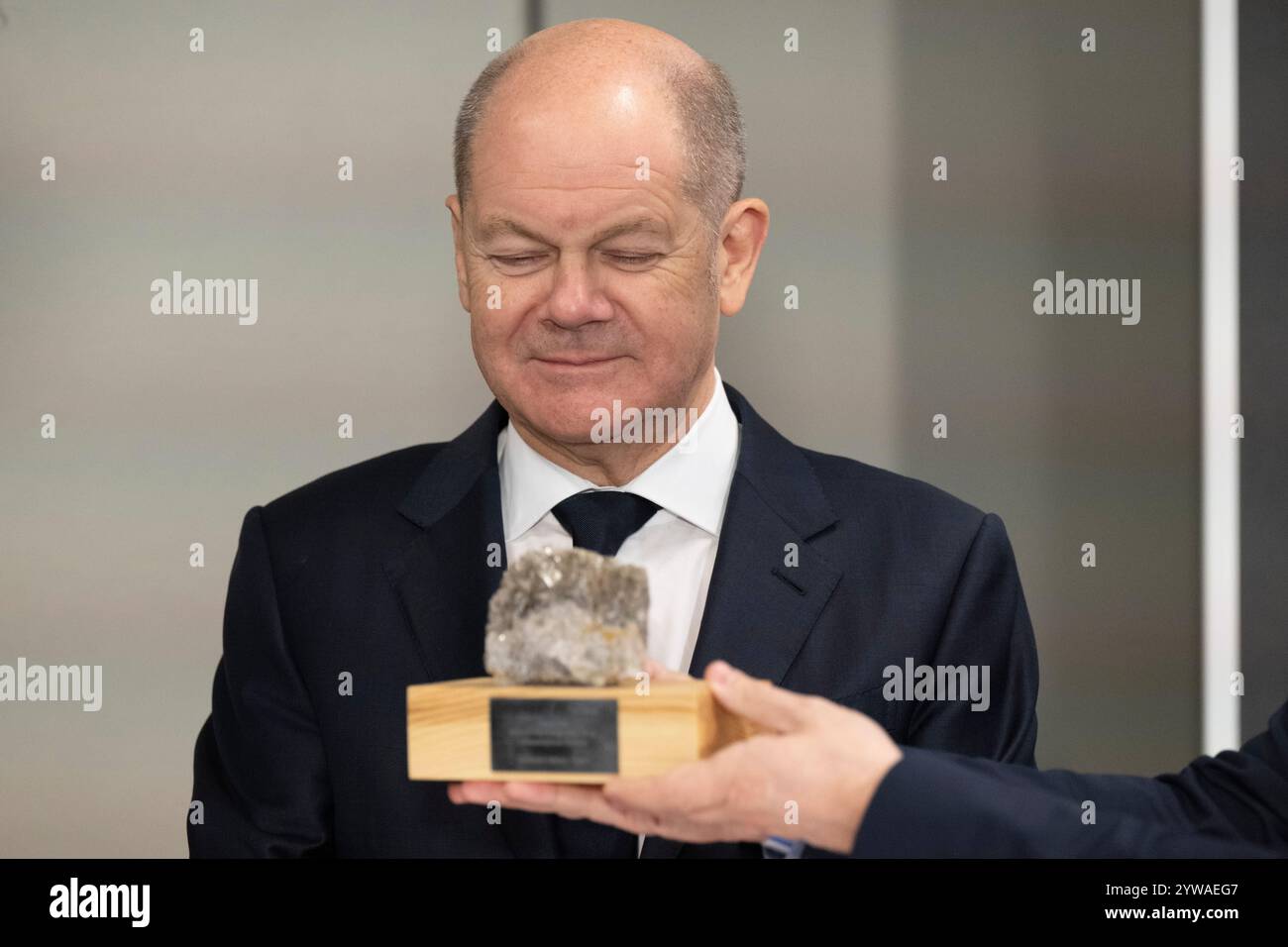 Freiberg, Deutschland. Dezember 2024. Bundeskanzler Olaf Scholz (SPD) untersucht ein lithiumhaltiges Gestein während einer kurzen Klassifizierung von Gesteinsproben im Stadt- und Bergbaumuseum. Im Erzgebirge erfahren der Bundeskanzler und der serbische Präsident mehr über den umweltfreundlichen Lithiumbergbau. Quelle: Sebastian Kahnert/dpa/Alamy Live News Stockfoto