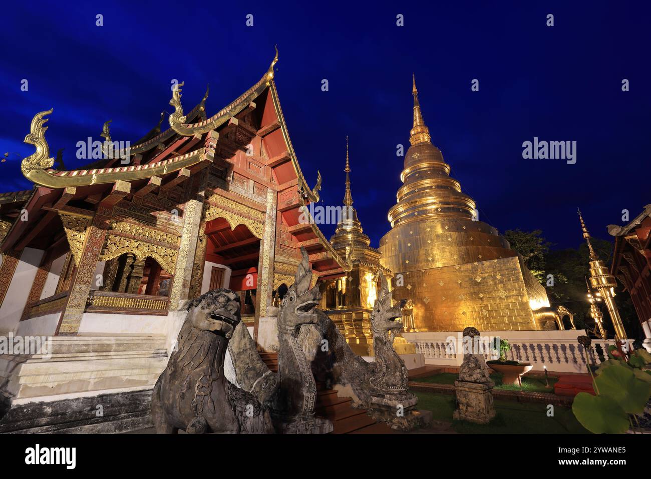 Kapelle und goldene Pagode am Wat Phra Singh Woramahawihan, beleuchtet in der Abenddämmerung, Chiang Mai, Thailand Stockfoto