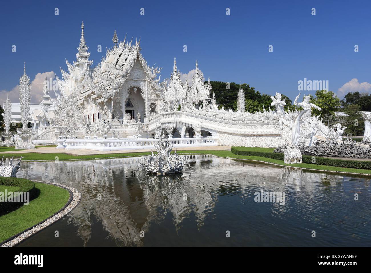 Wat Rong Khun (Weißer Tempel) spiegelt sich im Wasser an einem sonnigen Tag in Chiang Rai, Thailand Stockfoto