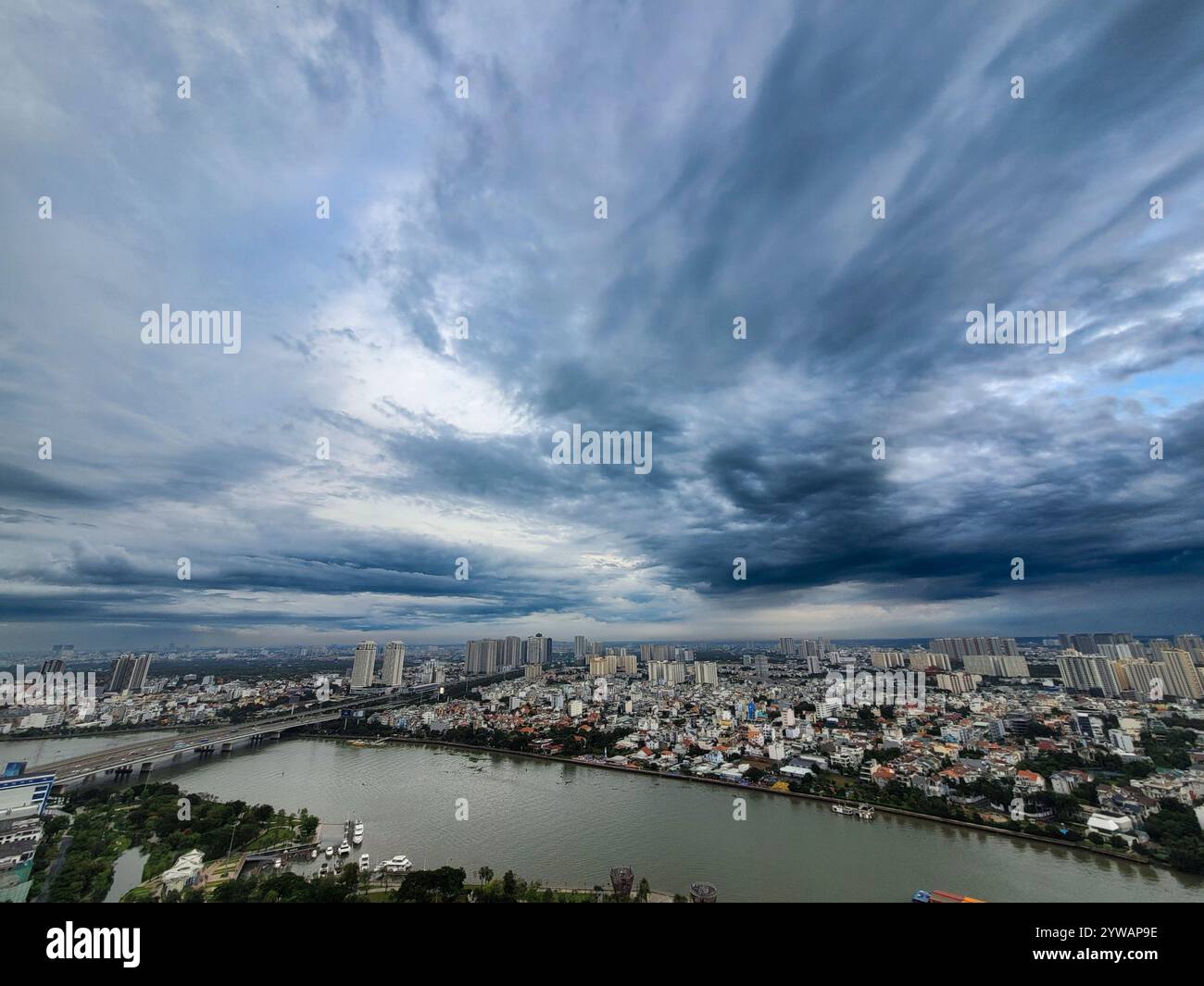 Eine Stadt mit einem großen Gewässer im Hintergrund. Der Himmel ist bewölkt und die Stadt ist nachts beleuchtet Stockfoto