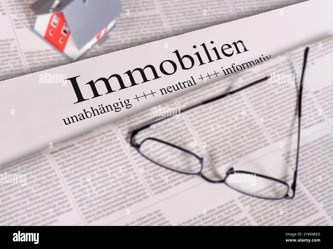 Zeitung für Immobilien auf einer Tageszeitung mit Überschrift Immobilien liegt eine Brille mit einem Modellhaus *** Zeitung für Immobilien auf einem dai Stockfoto