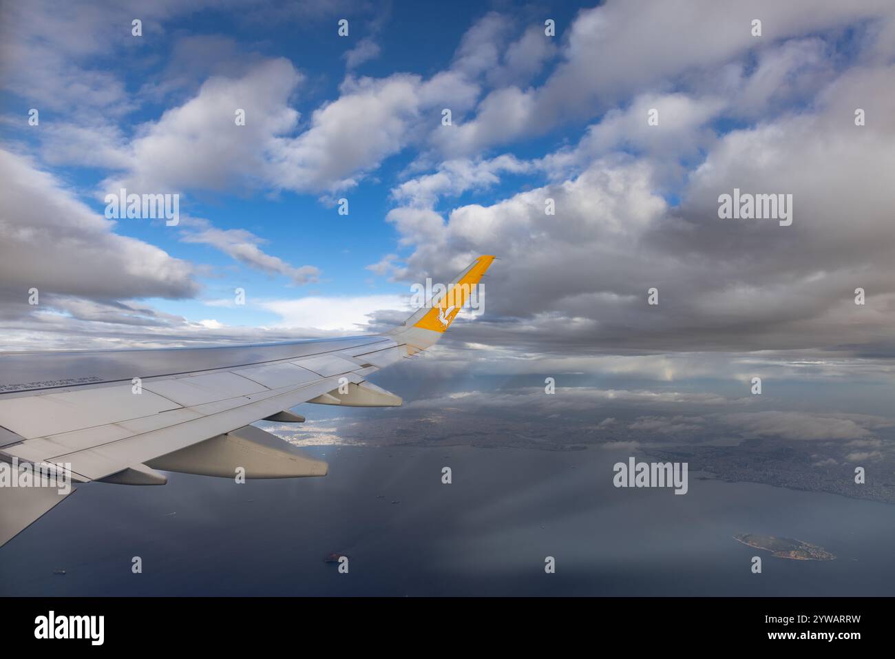 Ein Flugzeugflügel, der während der Landung oder des Starts an einem bewölkten Tag fotografiert wurde und das bewölkte Wetter und die nasse Pistenumgebung zeigt. Stockfoto
