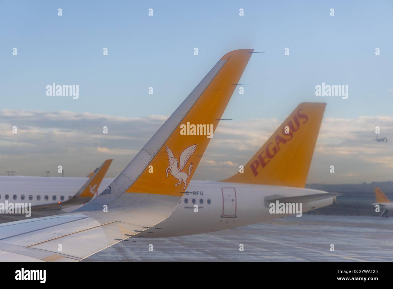 Ein Flugzeugflügel, der während der Landung oder des Starts an einem bewölkten Tag fotografiert wurde und das bewölkte Wetter und die nasse Pistenumgebung zeigt. Stockfoto