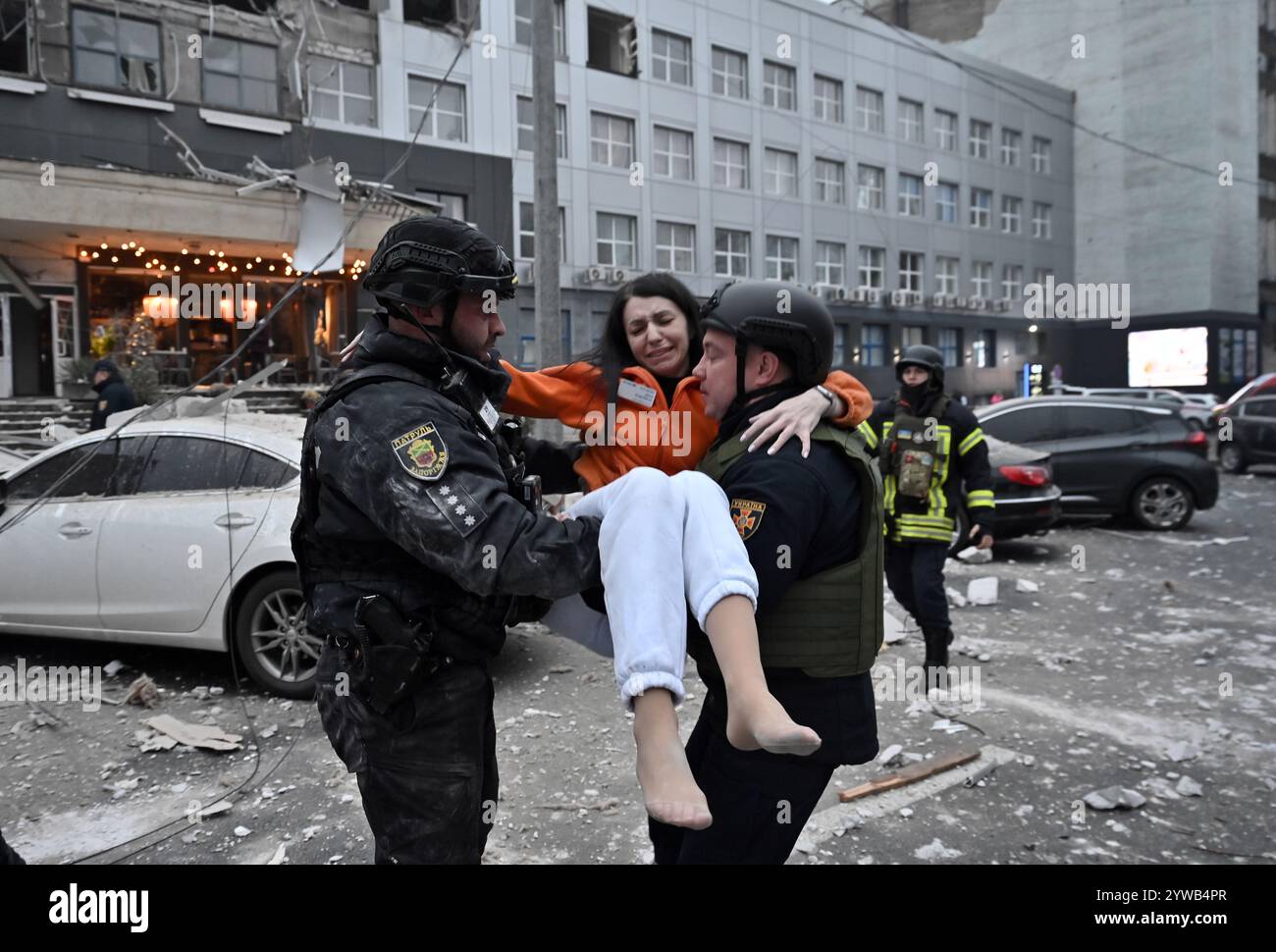 Zaporischzhia, Ukraine. Dezember 2024. ZAPORIZHZHIA, UKRAINE - 10. DEZEMBER 2024 - Polizeibeamte kommen an einer Frau vorbei, die aus einem Gebäude gerettet wurde, das durch einen russischen Raketenangriff zerstört wurde, Zaporischschschhia, Südostukraine. Drei Tote und mindestens 14 Verletzte. Ein Bürogebäude, ein medizinisches Zentrum und andere Gebäude sind beschädigt. Unter den Trümmern sind vielleicht Leute. Quelle: Ukrinform/Alamy Live News Stockfoto