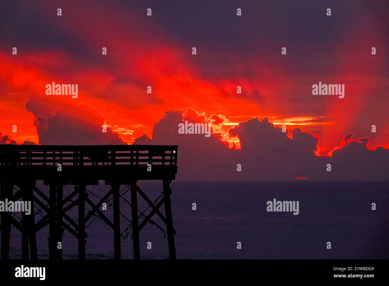 Isle Of Palms, Usa. Dezember 2024. Der Sonnenaufgang bricht hinter schweren Wolken, als eine Front durch das niedere Land schiebt, wodurch die Sonne über dem Atlantischen Ozean am Front Beach aufgeht, 10. Dezember 2024 in Isle of Palms, South Carolina. Das warme und feuchte Wetter weicht später in der Woche einer kalten Front. Quelle: Richard Ellis/Richard Ellis/Alamy Live News Stockfoto