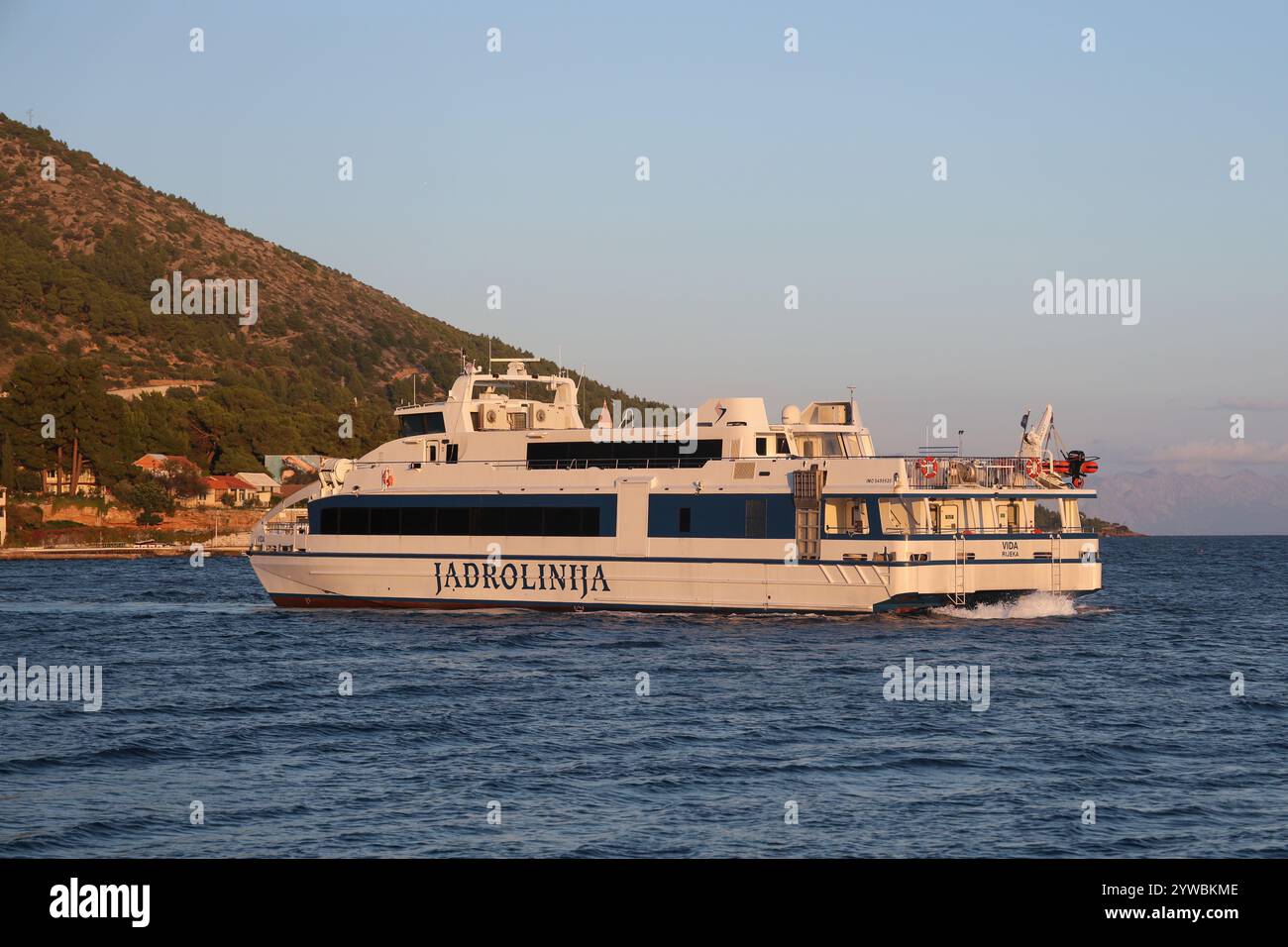 Die Fähre Jadrolinija verlässt den Hafen von Bol bei Sonnenuntergang, Insel Brac, Dalmatien, Kroatien, Europa. Stockfoto