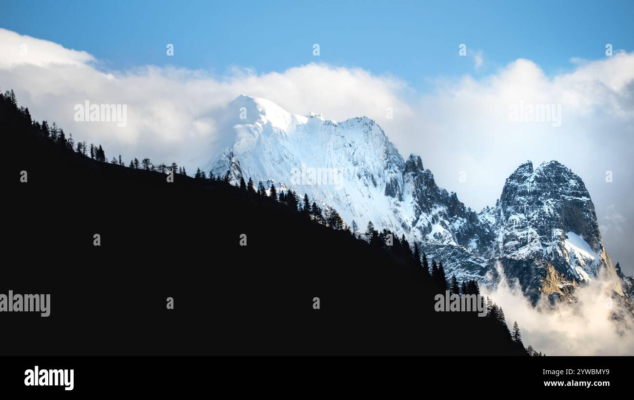 Landschaftsfotografie von Aiguille du Dru, teilweise bedeckt von einer Silhouette eines Berges mit Nadelbäumen, Französische Alpen, Kopierraum, 16:9 Stockfoto