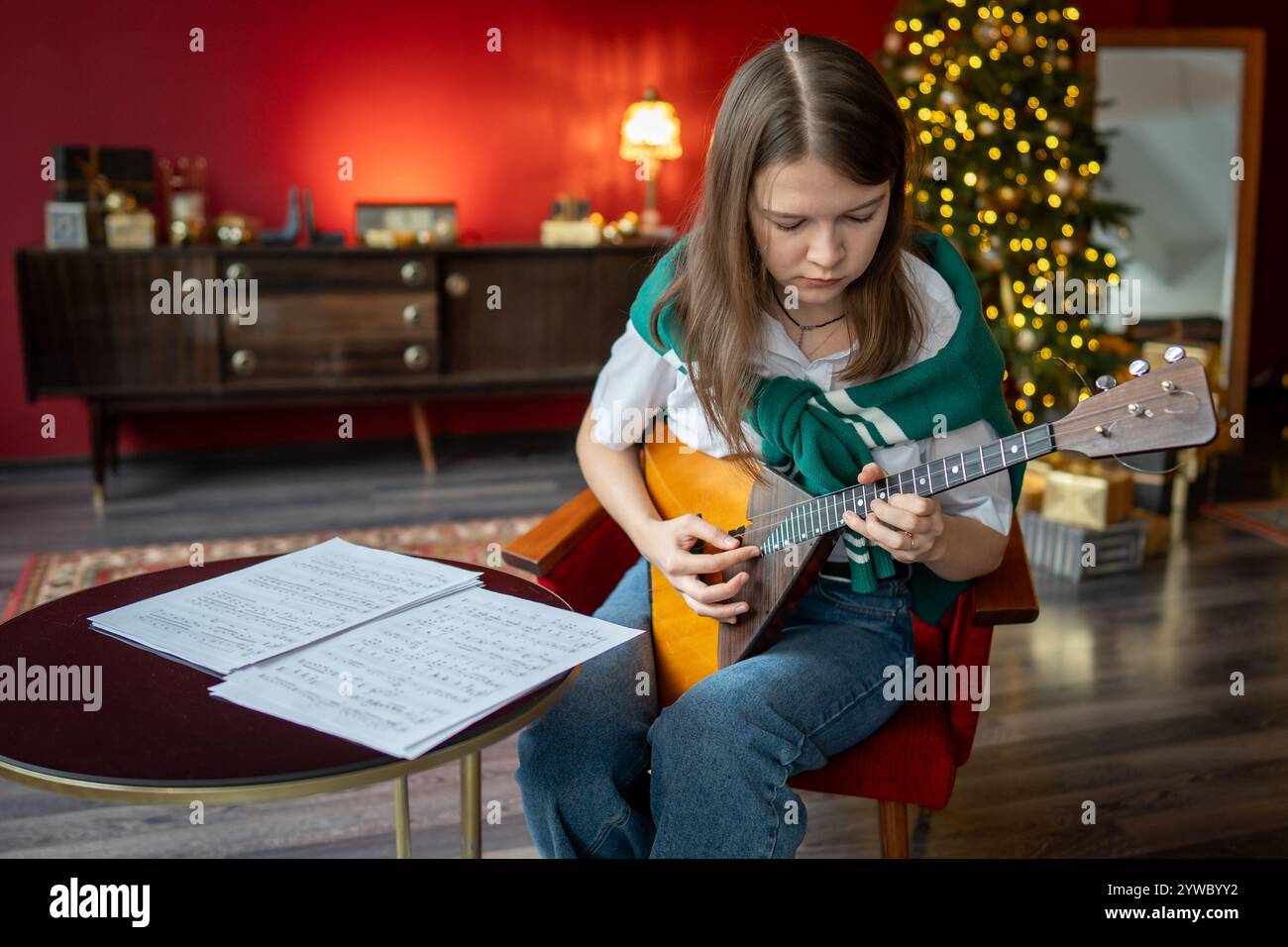 Konzentrierte Frau, die Balalaika-Lied einstudiert, Notizbogen liest, Konzert- oder Kurspraxis übt Stockfoto
