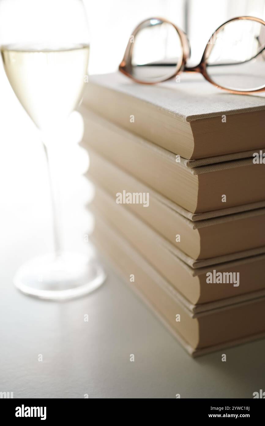 Gläser auf einem Stapel Bücher und ein Glas Weißwein Stockfoto
