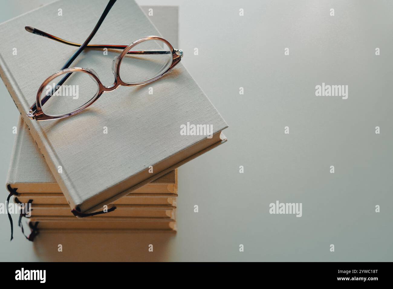 Eine Brille und ein Stapel Bücher auf weißem Hintergrund Stockfoto