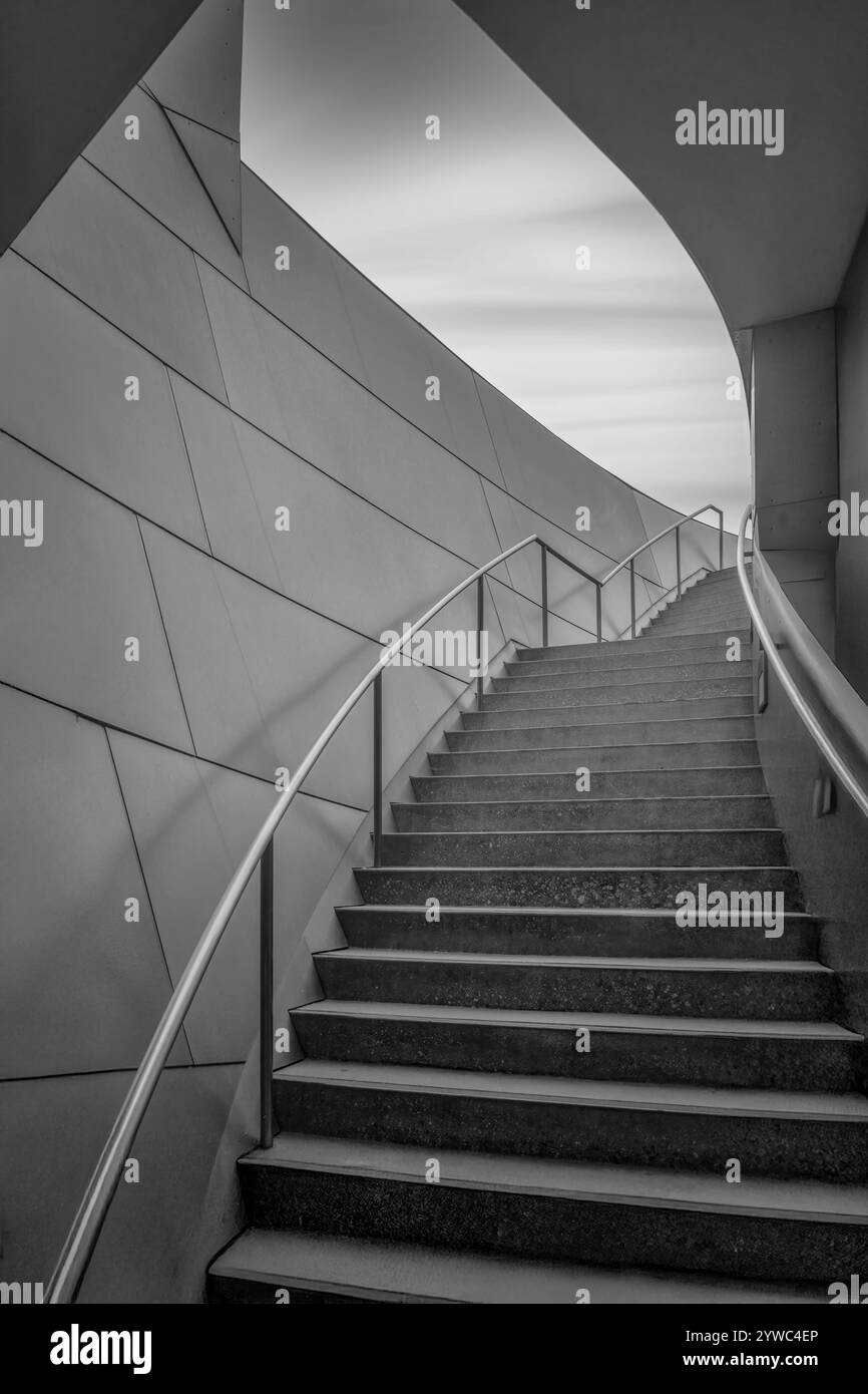 Architektonisches Detail einer spiralförmigen Metalltreppe innerhalb eines Gebäudes, eingerahmt vor einem ruhigen Innenhintergrund. Stockfoto