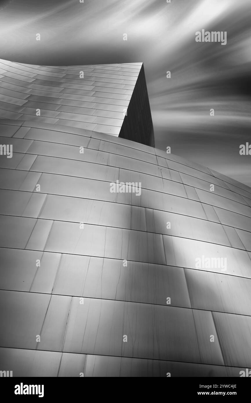 Geschwungene, glatte Metallfassungen unter einem sich schnell bewegenden bewölkten Himmel für dynamische Effekte. Stockfoto