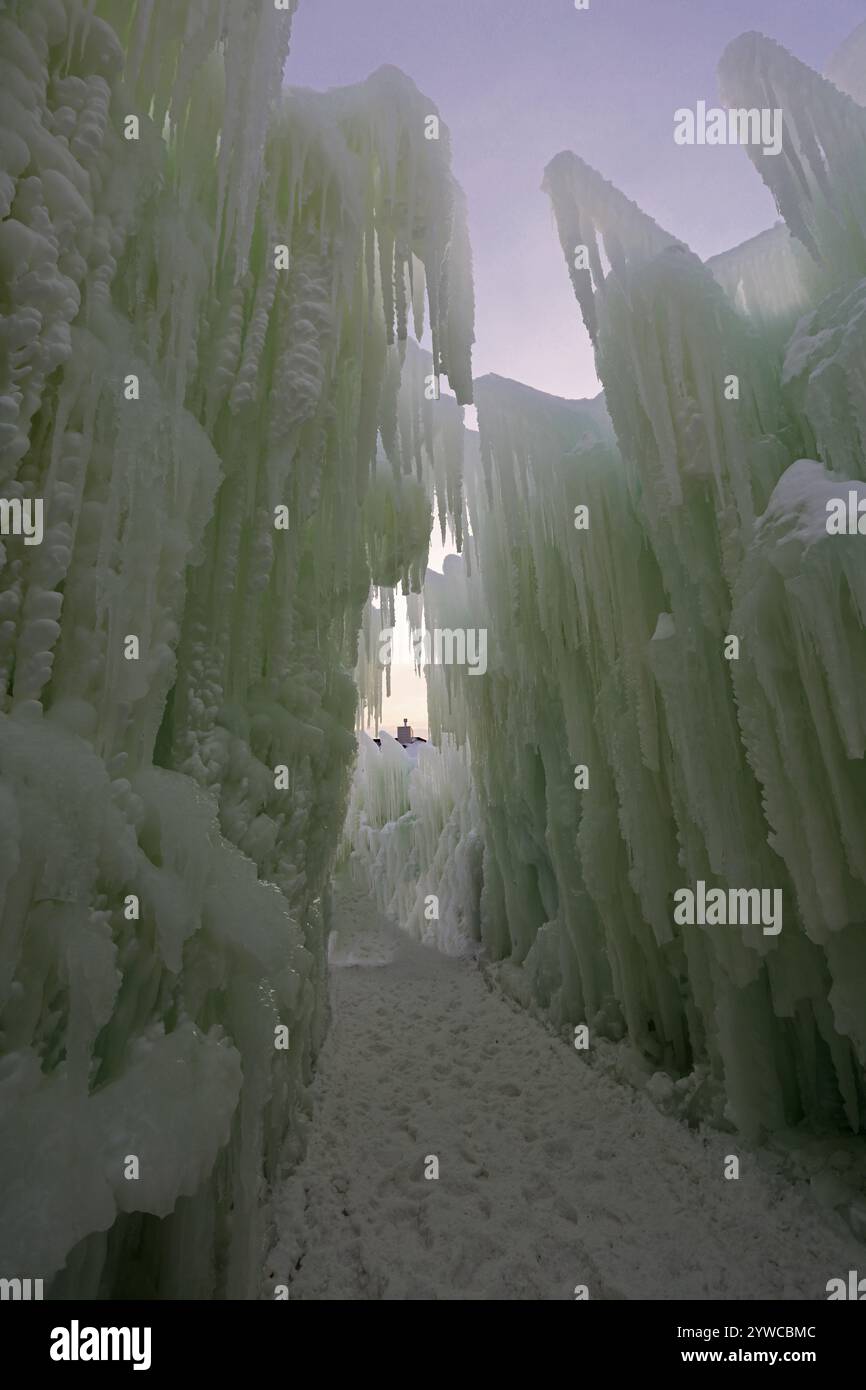 Ein Schneerad zwischen zwei Mauern aus gefrorenem Eis und Eiszapfen, der sich in Ice Castles im Genfer See, Wisconsin, USA, erhebt Stockfoto