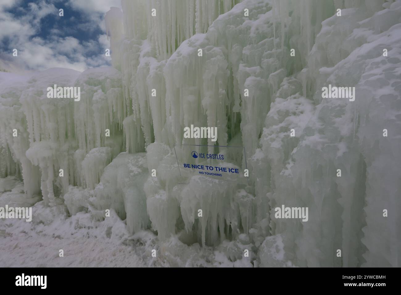 Eine Mauer aus gefrorenem Eis und Eiszapfen ragt über den Himmel mit einem humorvollen Schild in Ice Castles im Genfer See, Wisconsin, USA Stockfoto