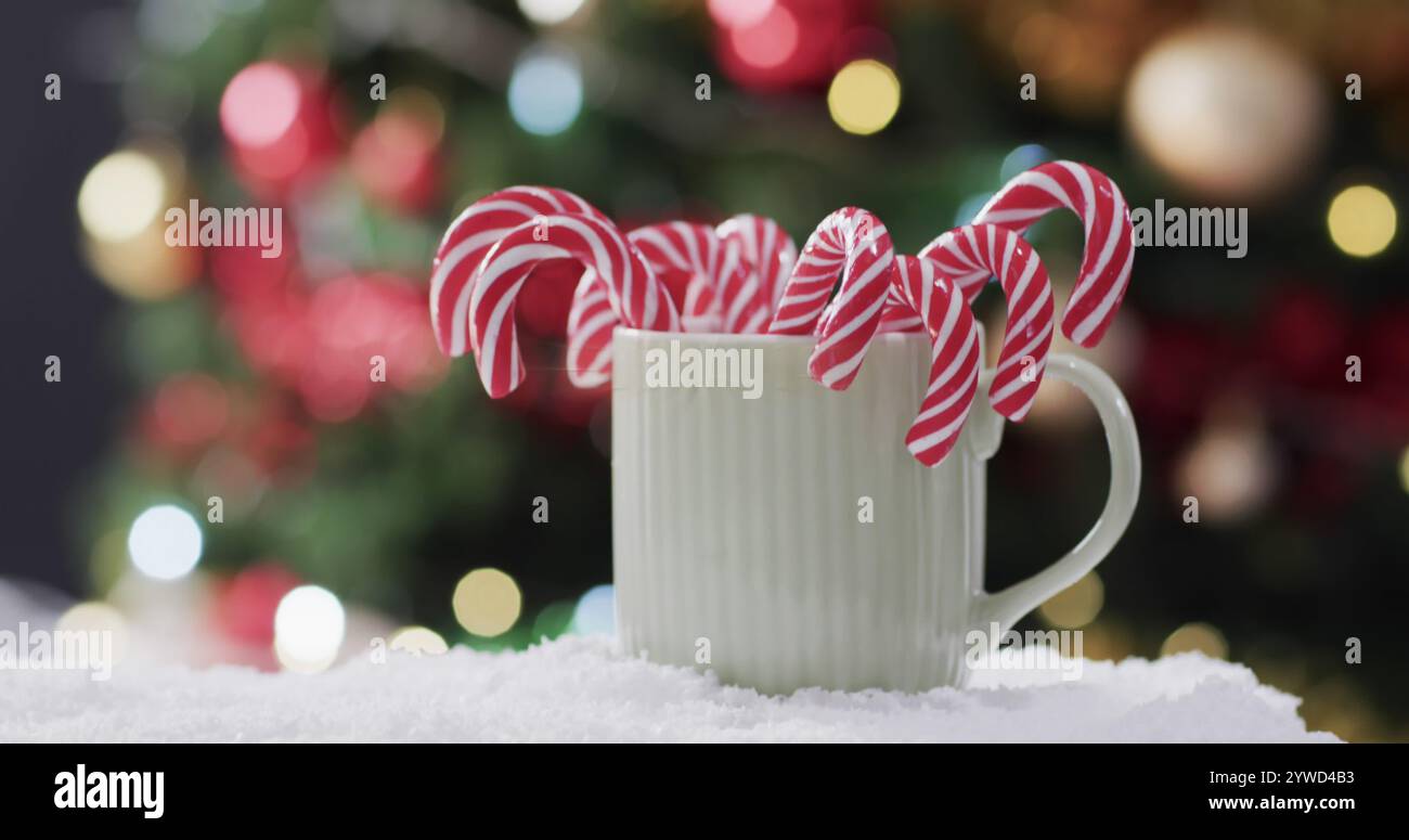 Ein festlicher Becher hält Bonbons vor einem verschwommenen Weihnachtsbaumhintergrund Stockfoto