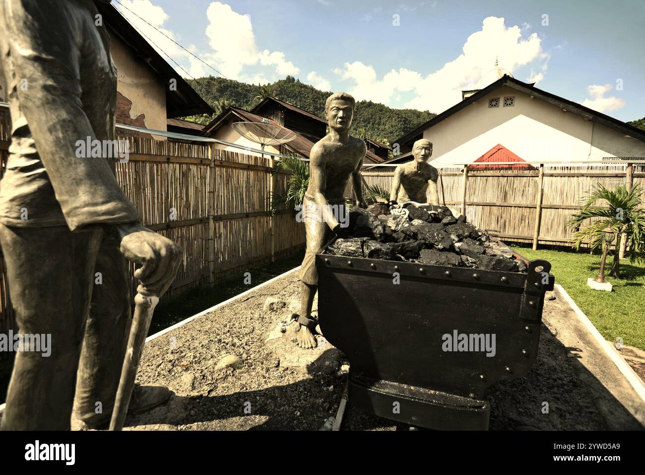 Skulpturen, die einen Aufseher zeigen, der Arbeiter beim Transport von Kohle mit einem Eisenbahnwagen in Sawahlunto, einer ehemaligen Kohlebergbaustadt in Sumatra, aufmerksam macht. Stockfoto