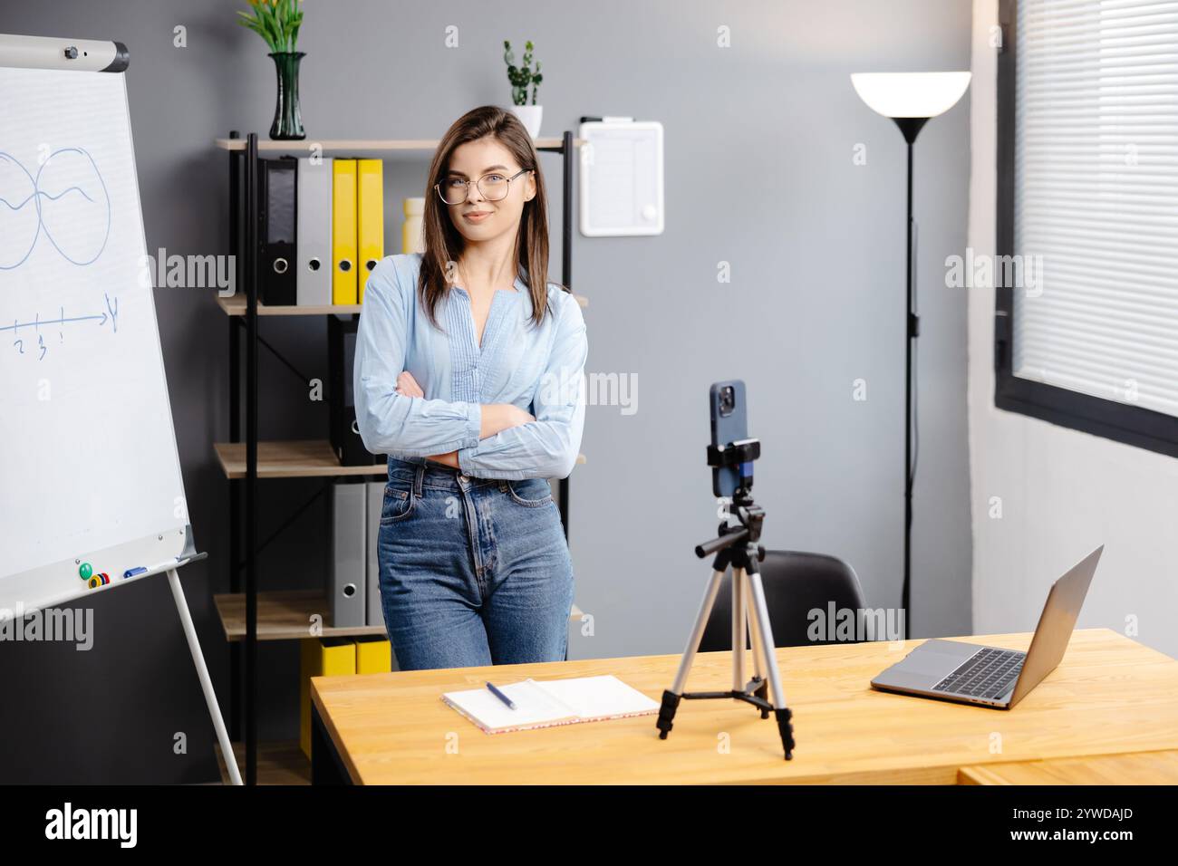 Junge Frau Mentorin nimmt Präsentationen auf, Webinar über Smartphone auf Stativ stehend, Lehrer Coach erklärt, hält Online-Unterricht, mit Telefon-Webc Stockfoto