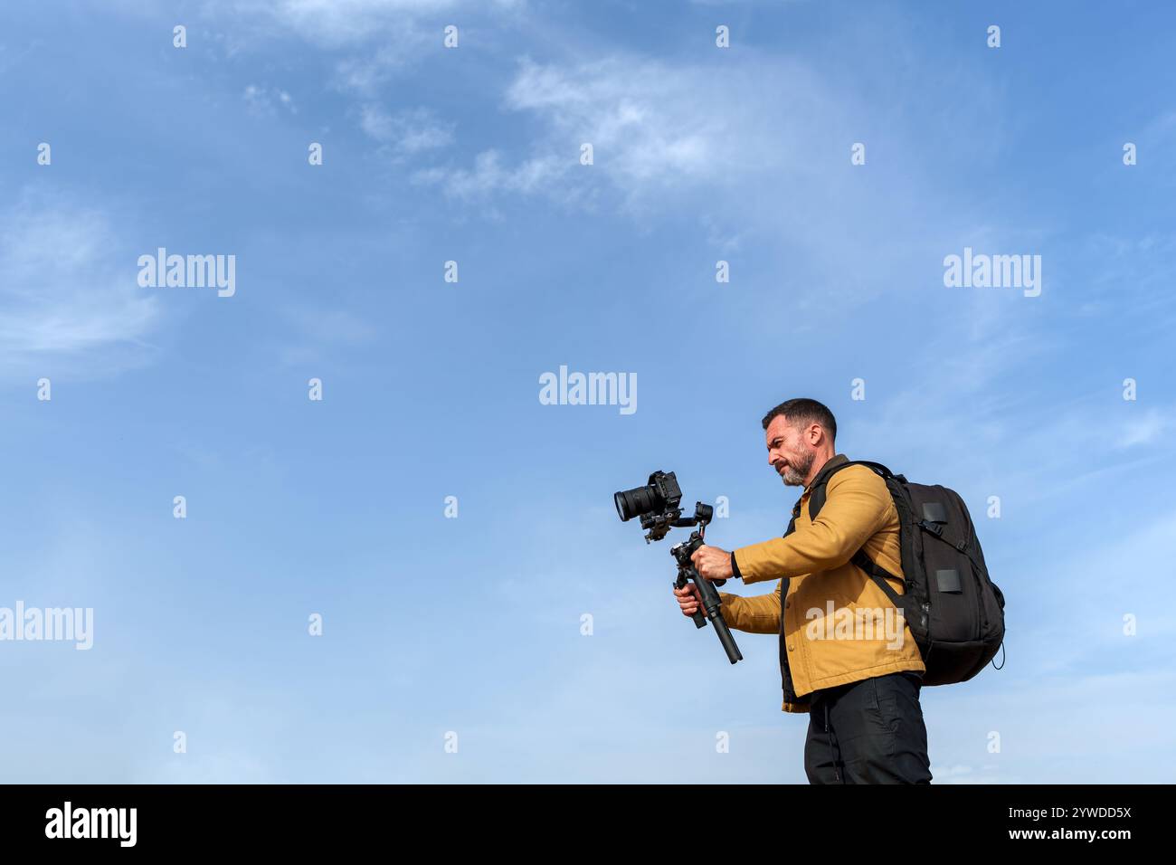 Videofilmer, der an einem sonnigen Tag mit professioneller Kamera und Gimbal-Stabilisator Aufnahmen im Freien aufnimmt Stockfoto