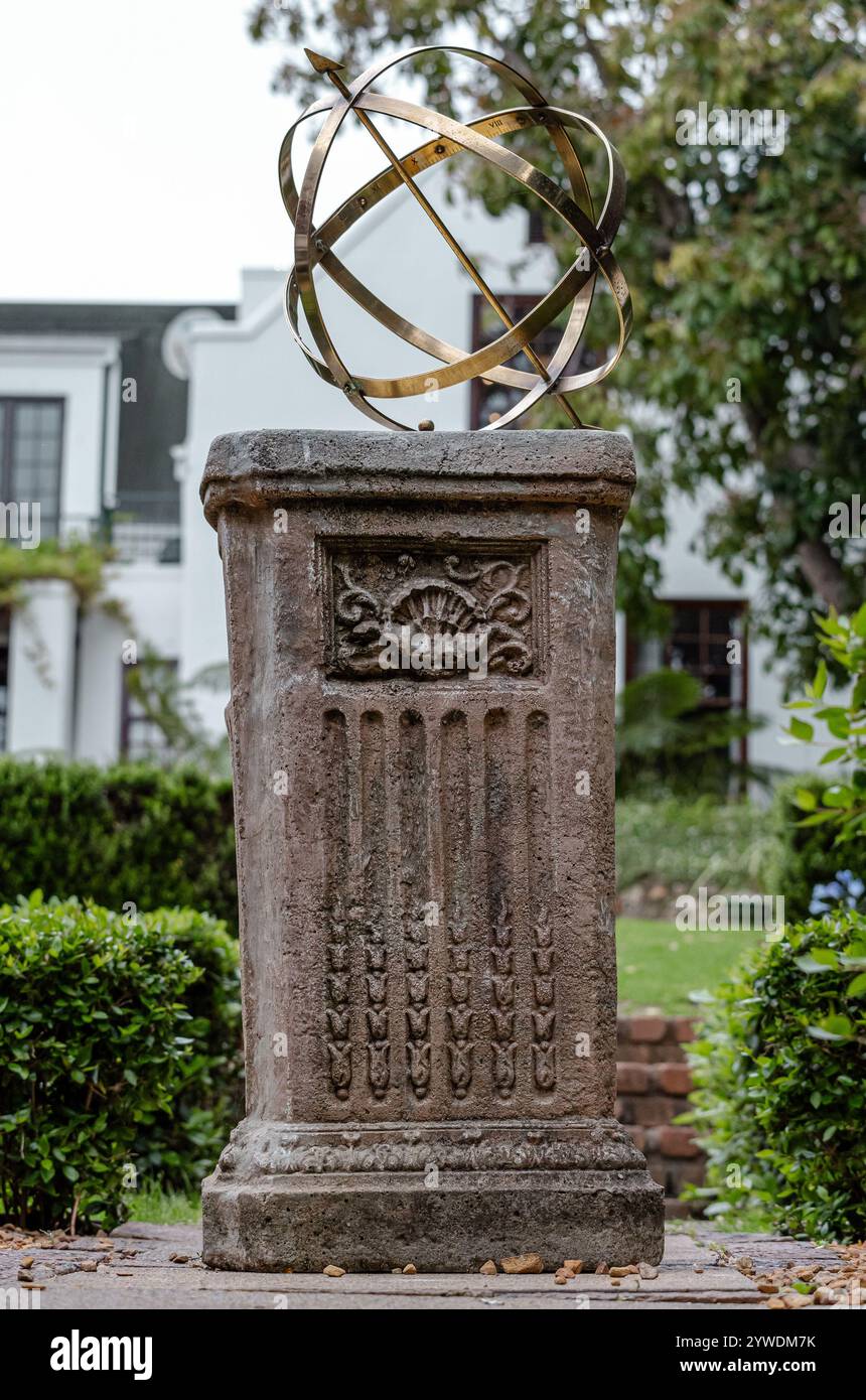 Große armillarische Sonnenuhr aus Messing oder Bronze mit erhöhten römischen Ziffern und Pfeil auf Sockel, Steinsockel mit Muster. Hinterhof Stockfoto