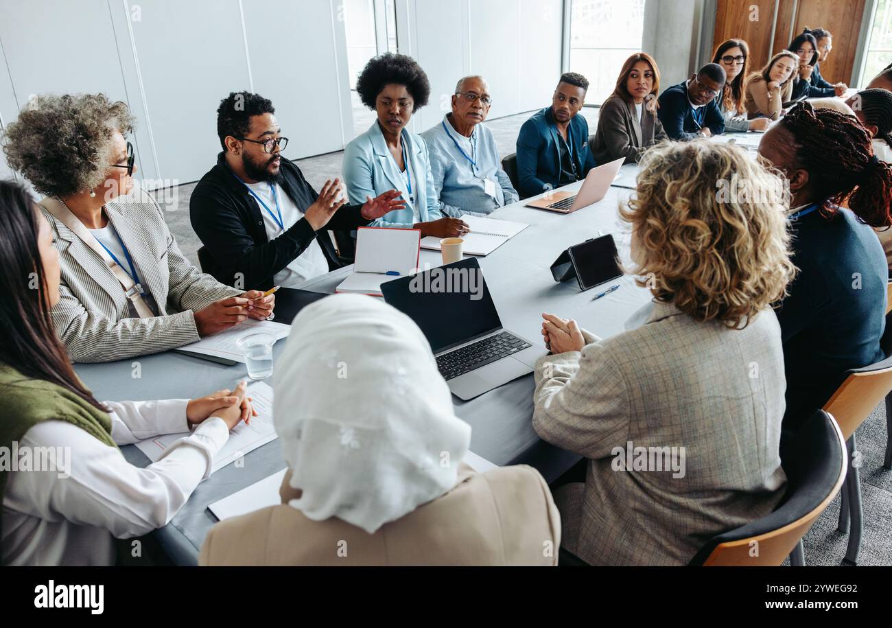 Multiethnische Gruppe von Geschäftsleuten, die an einer Strategie- und Brainstorming-Sitzung an einem Konferenztisch teilnahmen. Kollaborativ und konzentriert sich auf Teamarbeit A Stockfoto