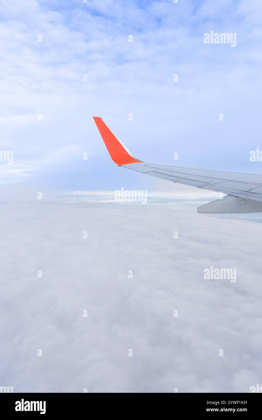 Ein hochauflösendes Foto eines Flugzeugflügels und blauen Himmels, das durch ein Flugzeugfenster betrachtet wird, symbolisiert Luftfahrt, Reise, Urlaub und frühe Buchung Stockfoto