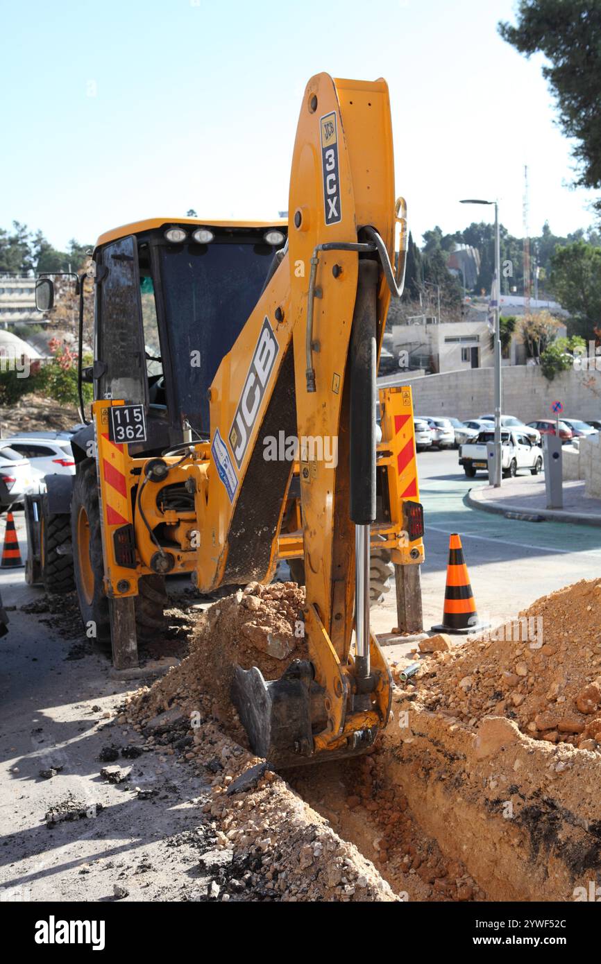 Die Schaufel des Bulldozers wurde von einem hydraulischen zylindrischen Arm bewegt und grub einen Graben in einer Nachbarstraße, um elektrische Kabel darin zu verlegen Stockfoto