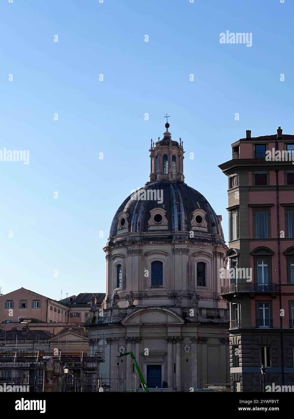 Eine wunderschöne historische Kuppel erhebt sich inmitten städtischer Gebäude unter einem klaren blauen Himmel und zeigt klassische Architektur mit elegantem Design. Rom, Italien. Stockfoto