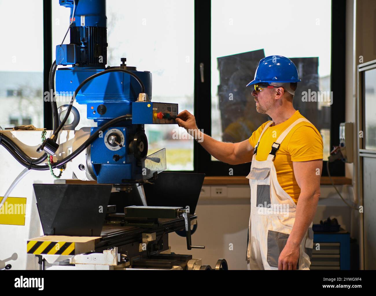 Fabrikarbeiter, der eine Fräsmaschine bedient, demonstriert die Sicherheit am Arbeitsplatz mit angemessener Kleidung und konzentrierter Aufmerksamkeit. Stockfoto Fabrikarbeiter, der eine Fräsmaschine bedient, demonstriert die Sicherheit am Arbeitsplatz mit angemessener Kleidung und konzentrierter Aufmerksamkeit. Stockfoto
