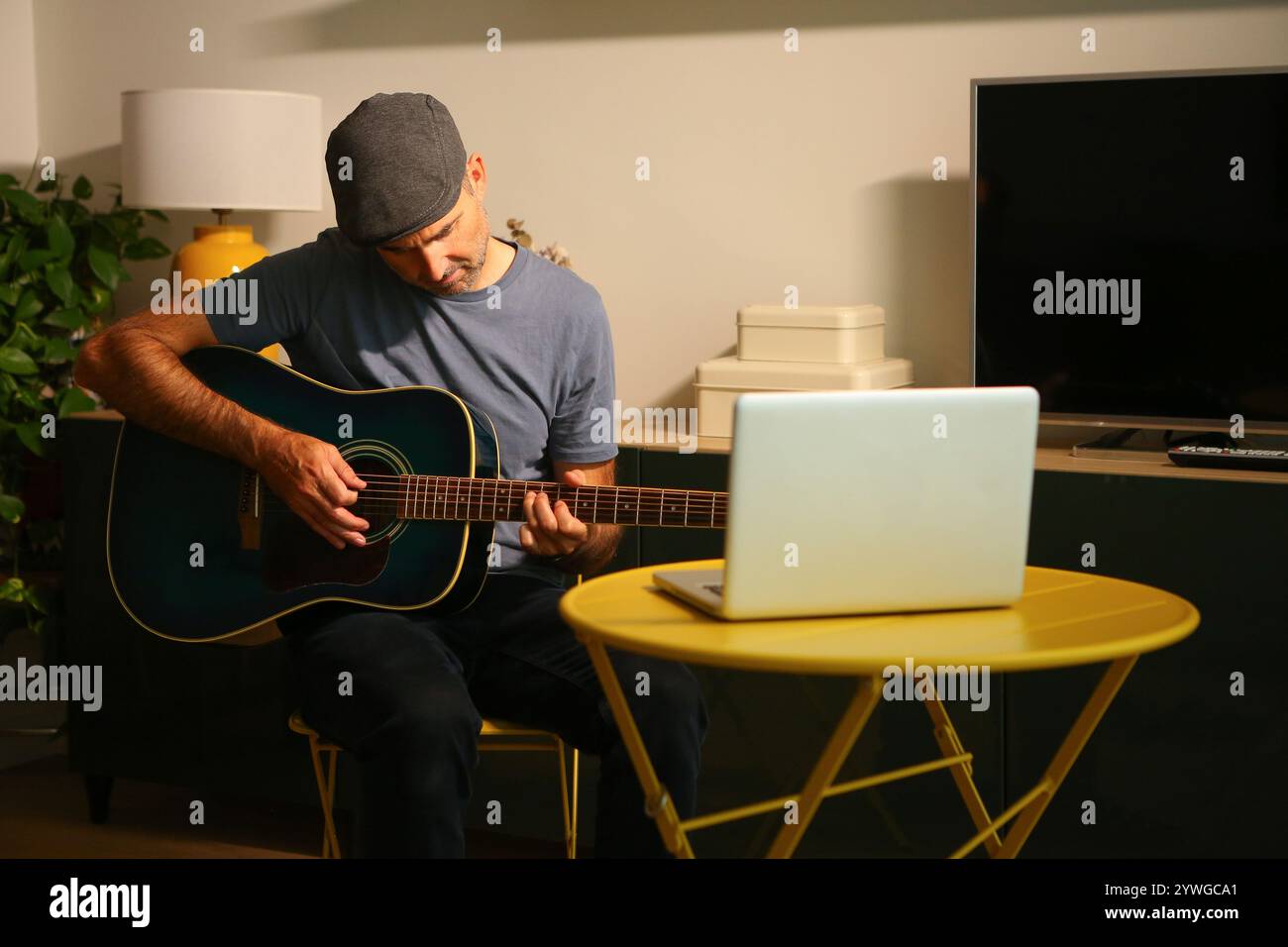Ein Mann, der vor dem Computer sitzt und Online-Musikunterricht übt Stockfoto
