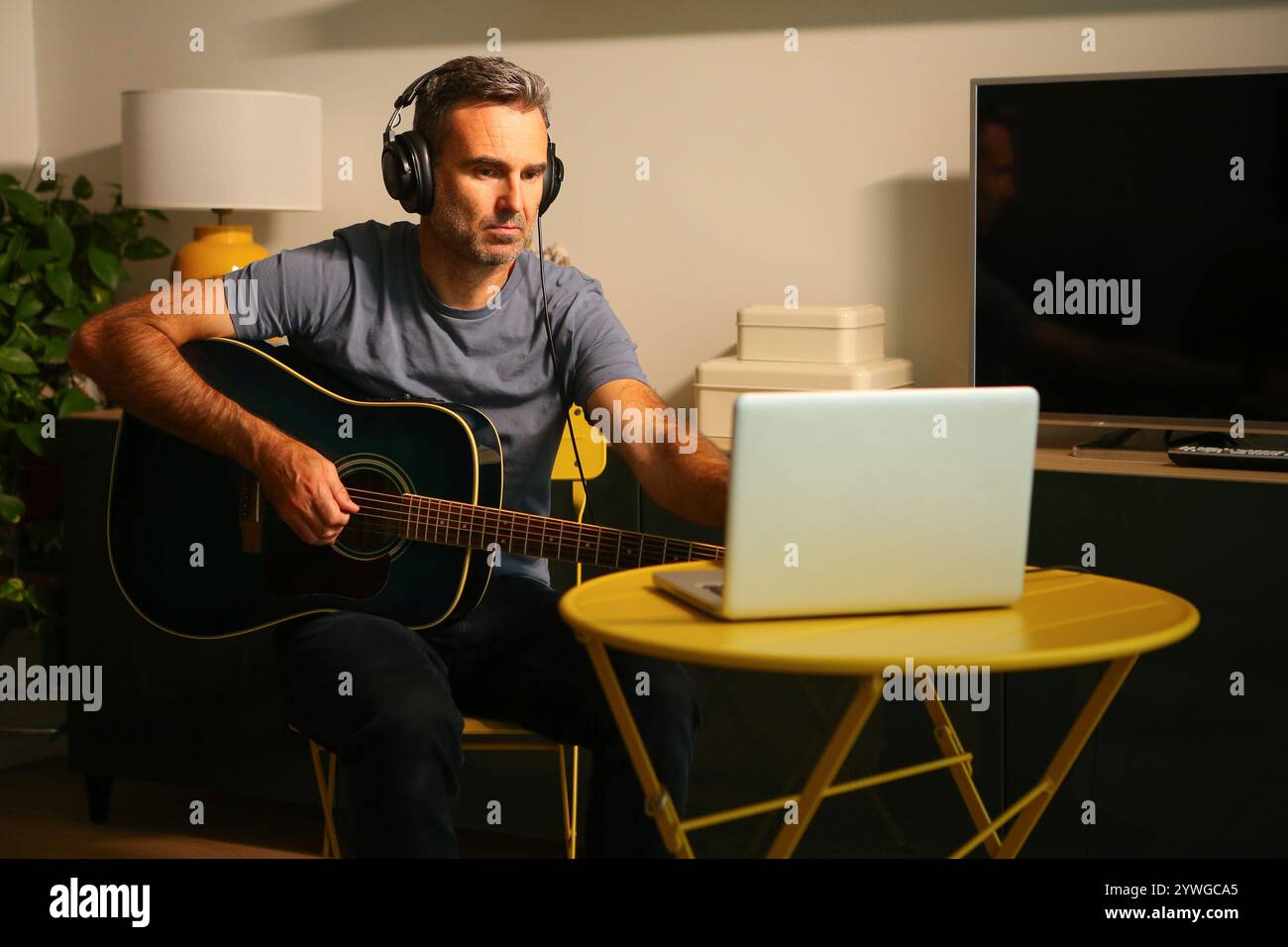 Ein Mann, der vor dem Computer sitzt und Online-Musikunterricht übt Stockfoto