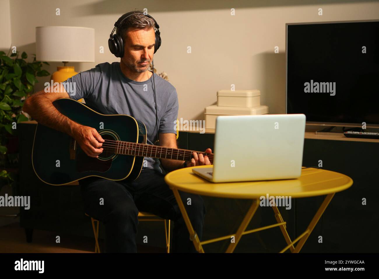 Ein Mann, der vor dem Computer sitzt und Online-Musikunterricht übt Stockfoto