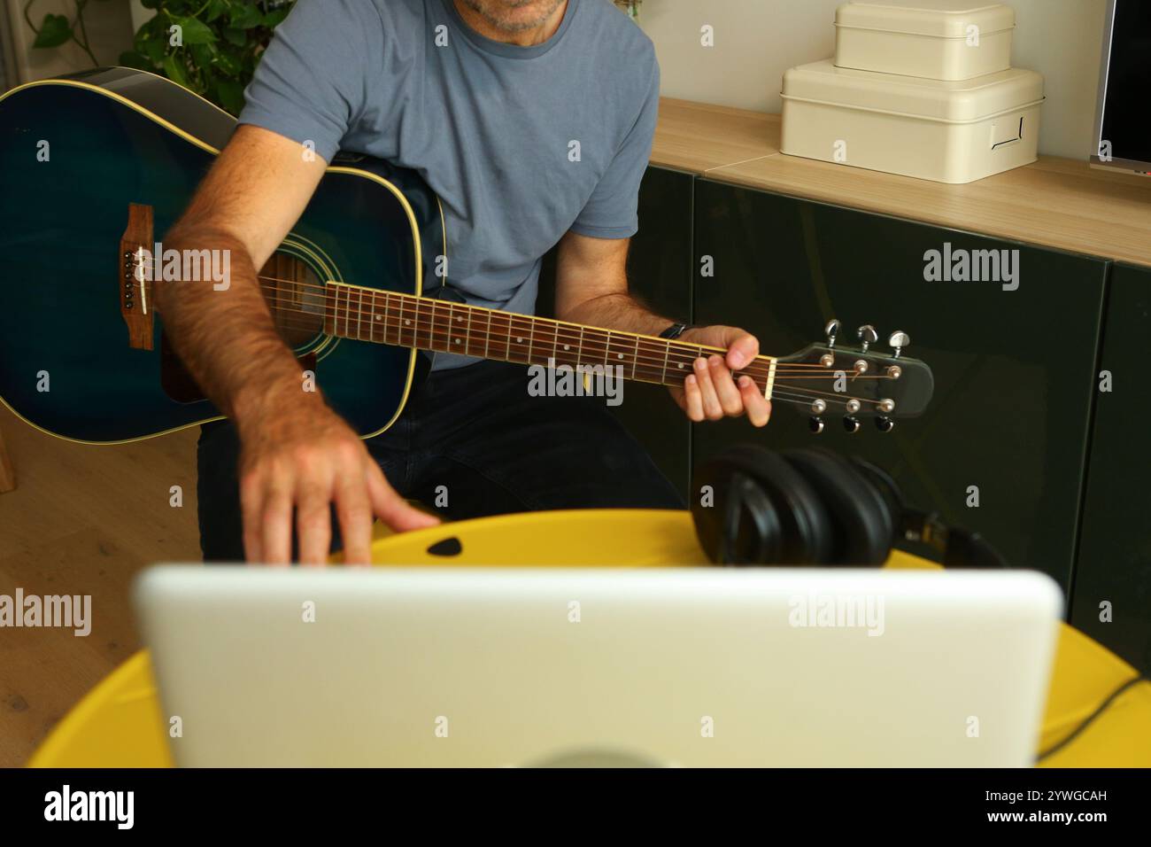 Ein Mann, der vor dem Computer sitzt und Online-Musikunterricht übt Stockfoto