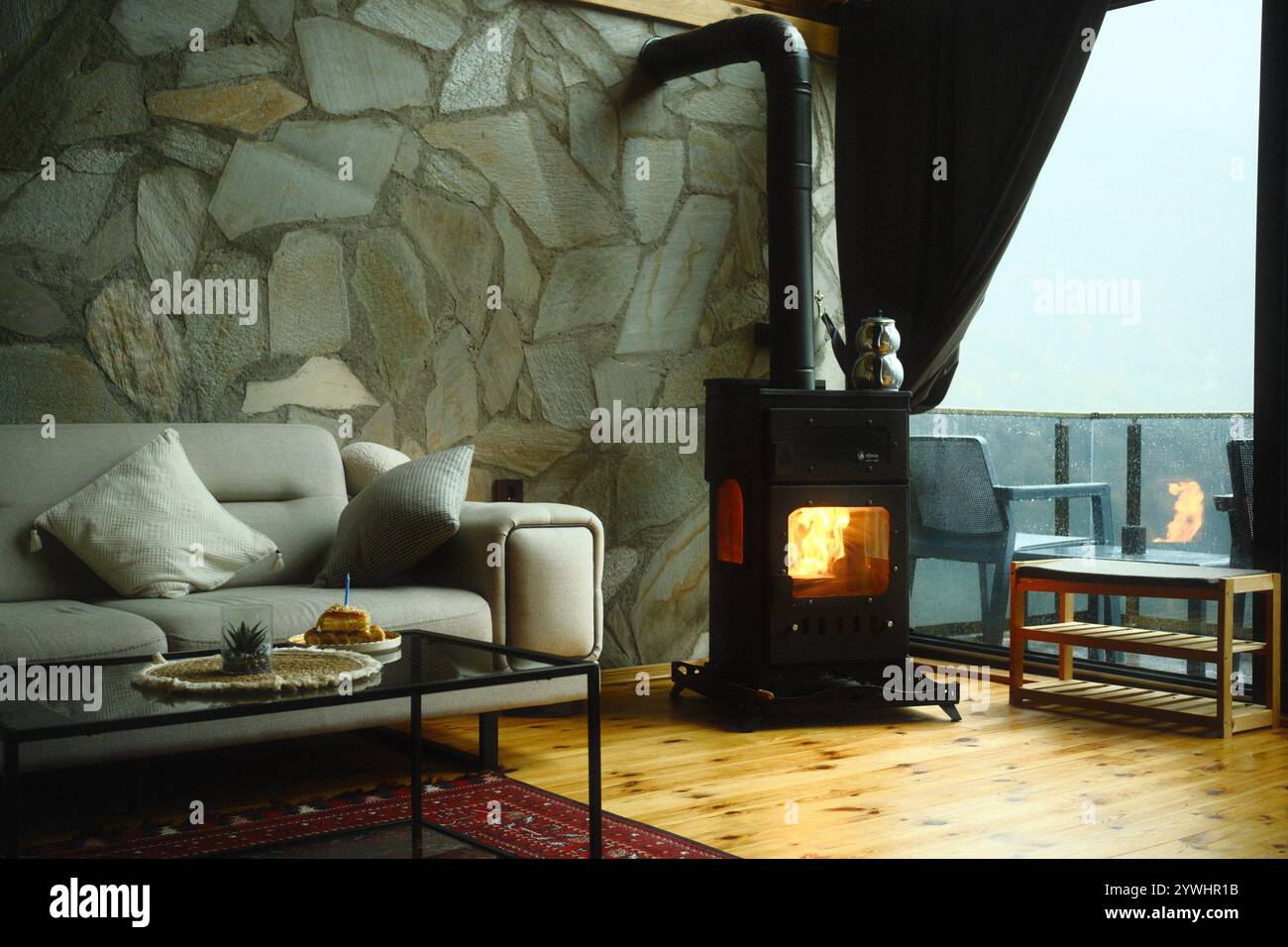 Ein warmes, ästhetisches Wohnzimmer mit modernem Kamin und Tageslicht in einem bergigen Bereich Stockfoto