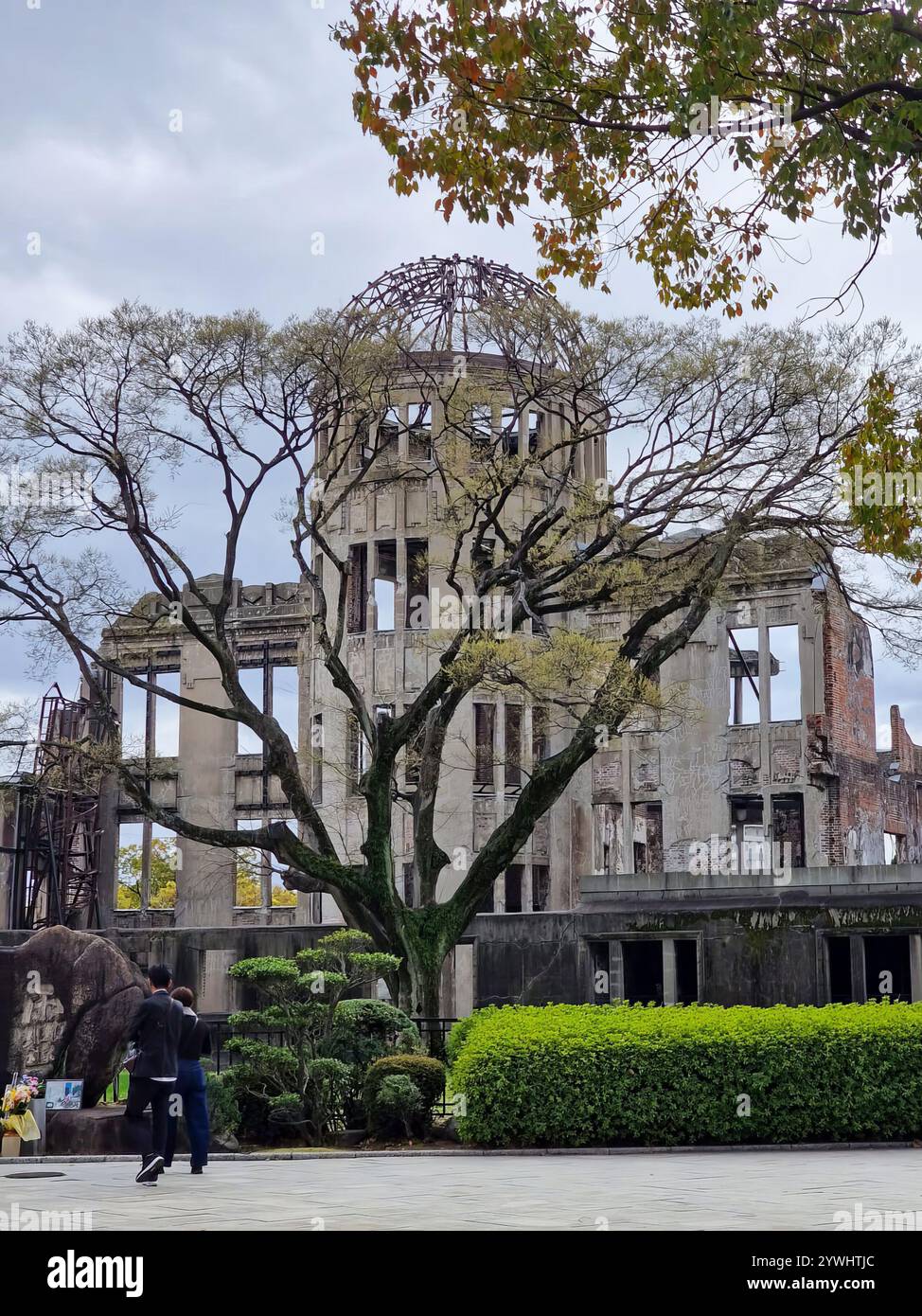 Das Hiroshima Peace Memorial, oder Atombombendom, steht inmitten von Bäumen und Grünflächen in Hiroshima, Japan, und bietet Besuchern zusätzliche Maßstäbe und Verbindungen. Stockfoto