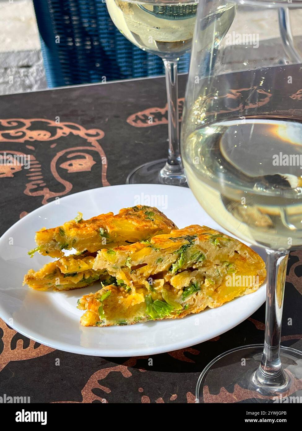 Spanisches Omelett mit Gemüse und Weißweingläsern. Spanien. - Smartphone-aufgenommenes Stockfoto