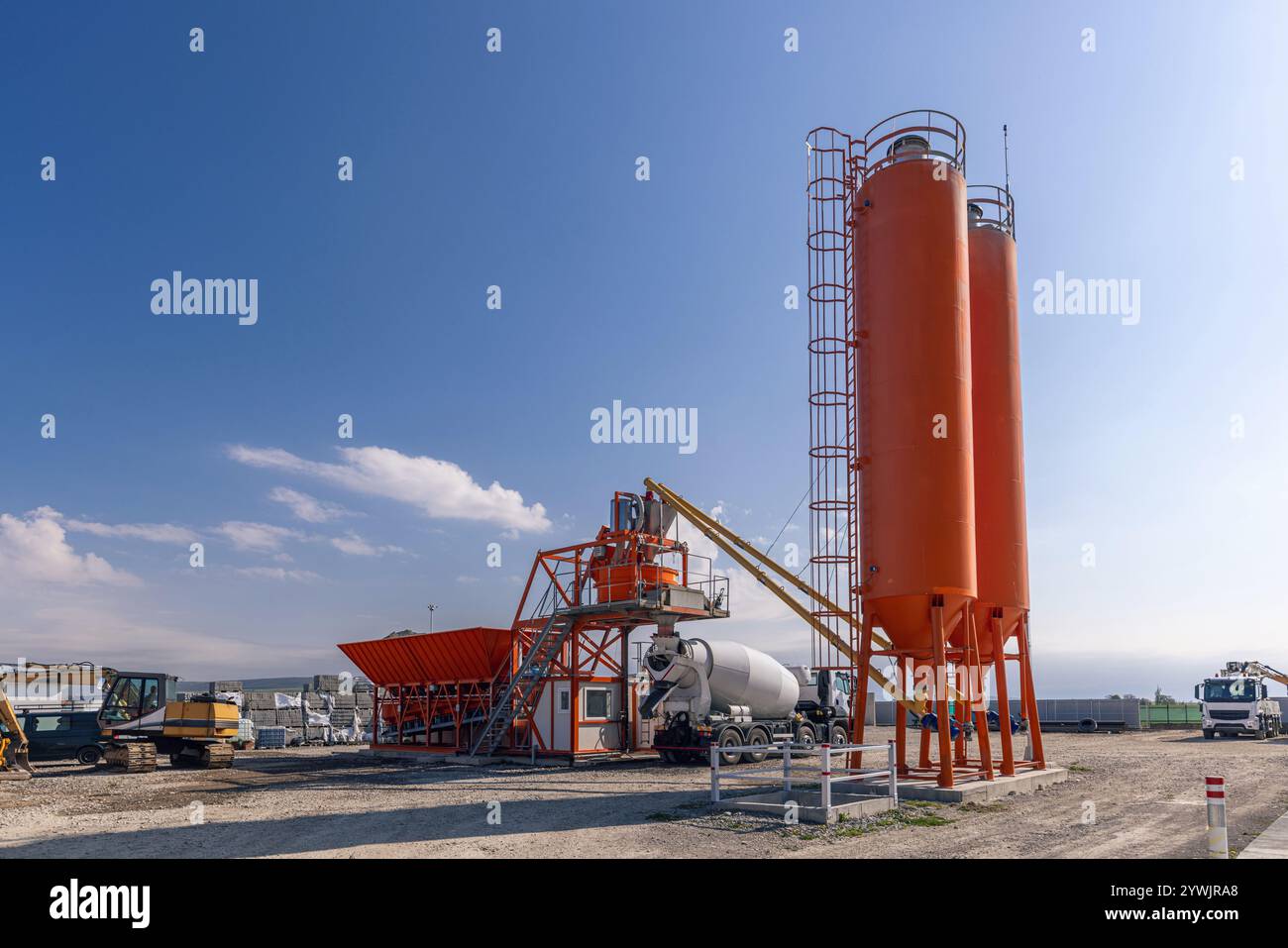 Betonmischanlage mit Mischturm und Zementwagen, die unter klarem Himmel geparkt sind Stockfoto