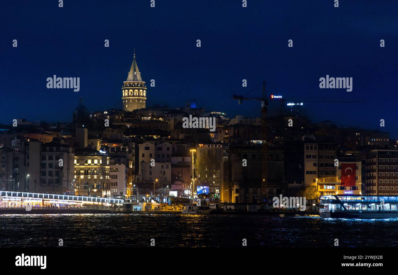Ein atemberaubender nächtlicher Blick auf Istanbul mit dem berühmten Galata-Turm, der vor dem dunklen Himmel beleuchtet wird, mit der lebendigen Galata-Brücke. Stockfoto