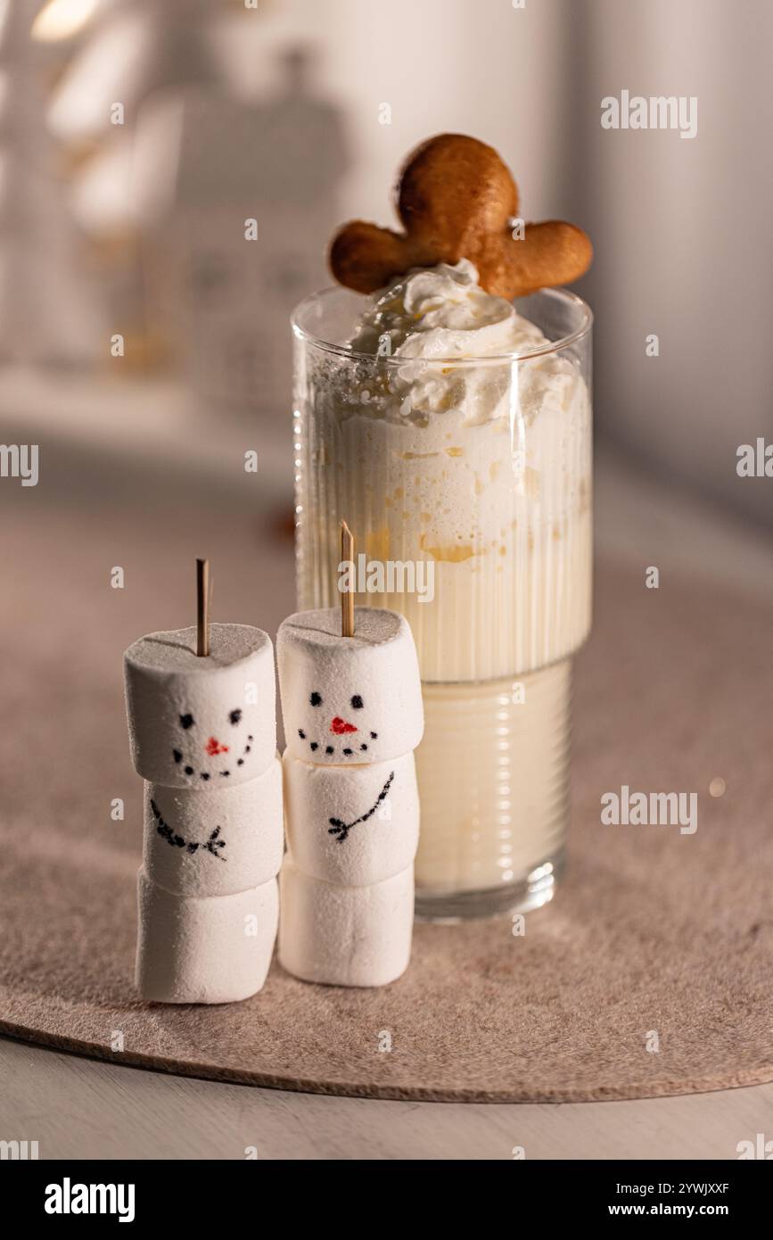 Eierlikör mit Schlagsahne und Lebkuchenmännchen, neben zwei Schneemännern Stockfoto