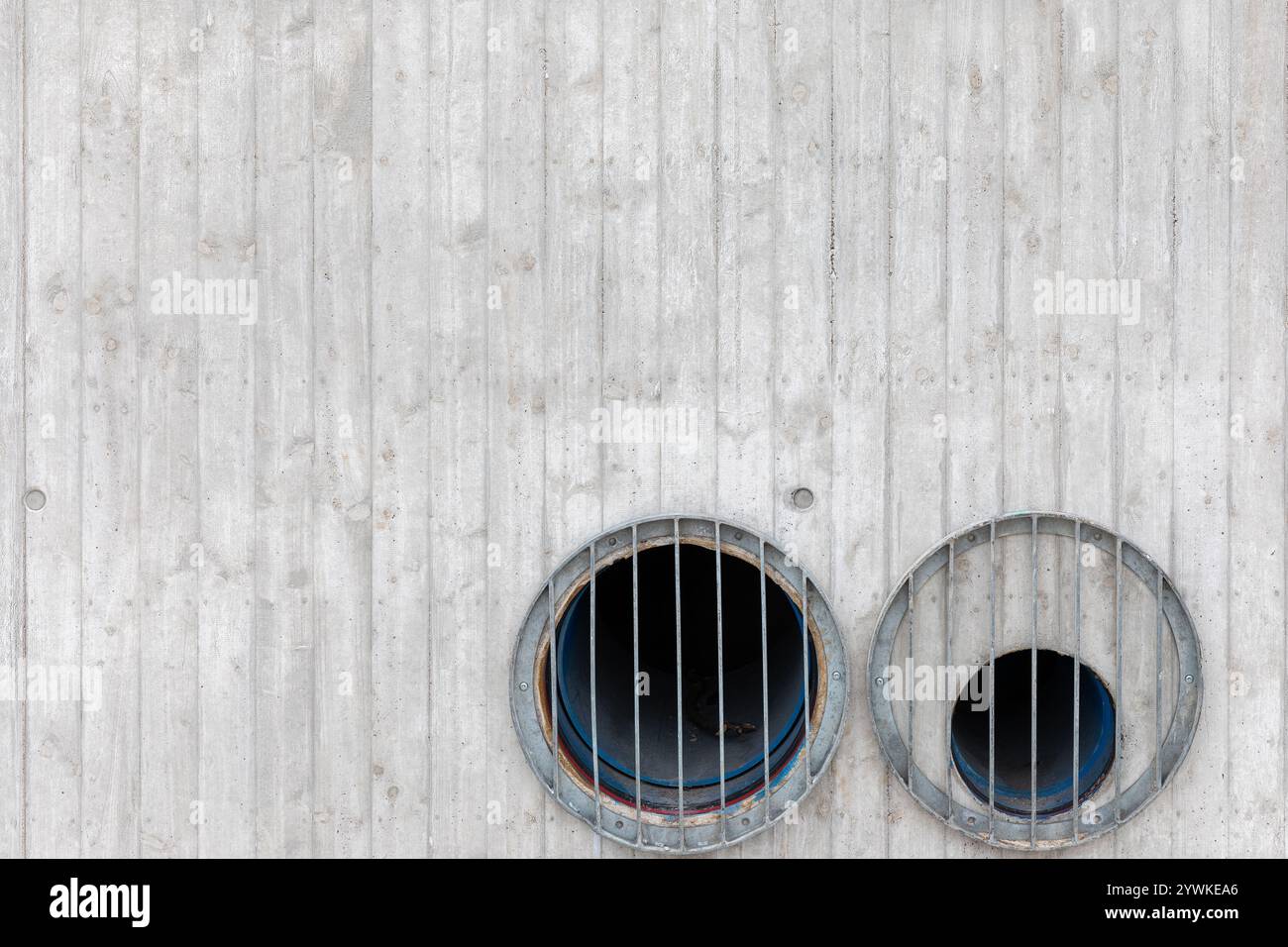 Strukturierte graue Betonwand mit zwei Löchern – abstrakter Hintergrund oder industrielle Oberfläche Stockfoto