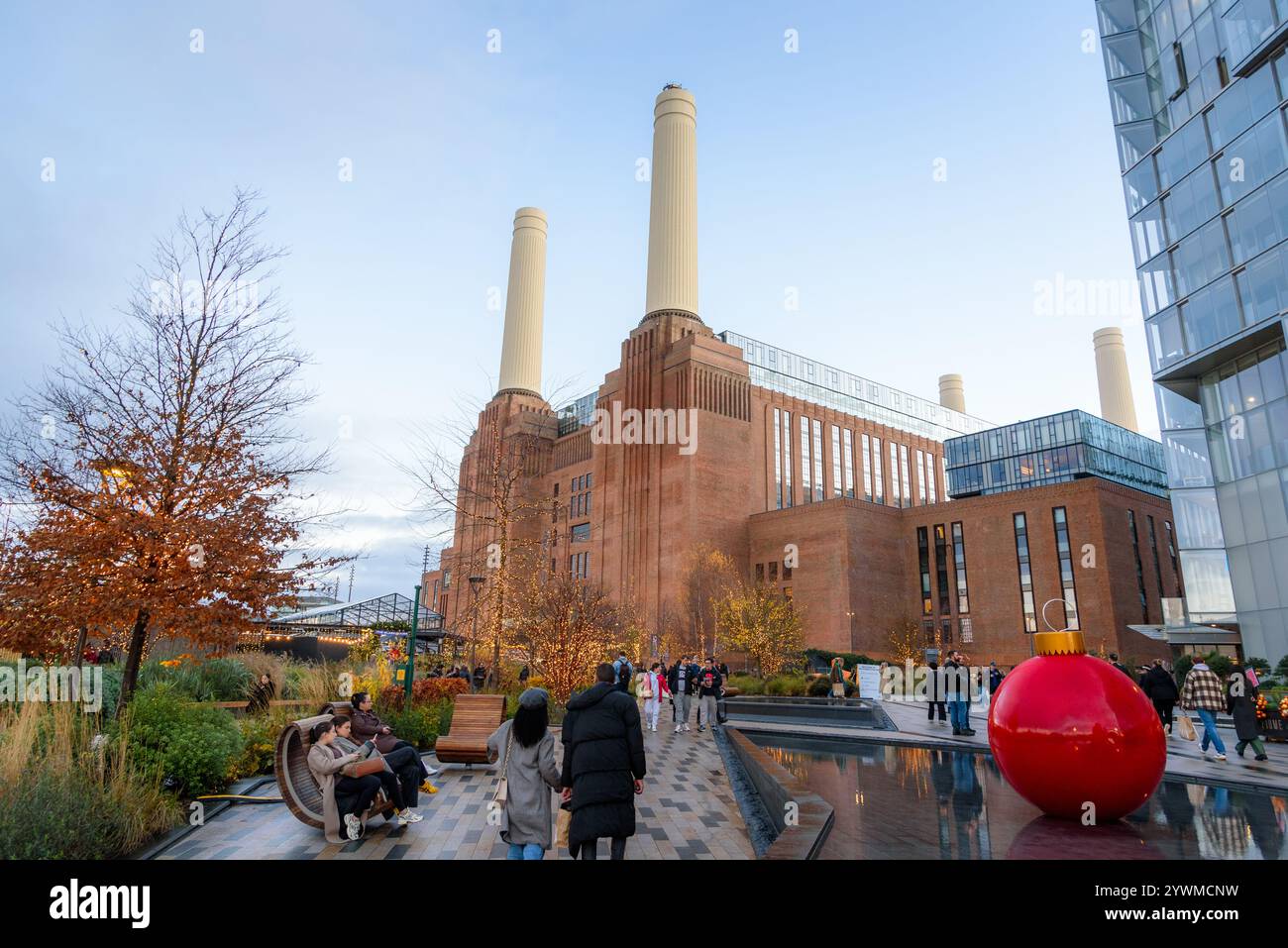 Menschen schlendern auf einem Fußweg, gesäumt von Chistmas Ligthen und Riesenkugeln im Battersea Power Station Stockfoto