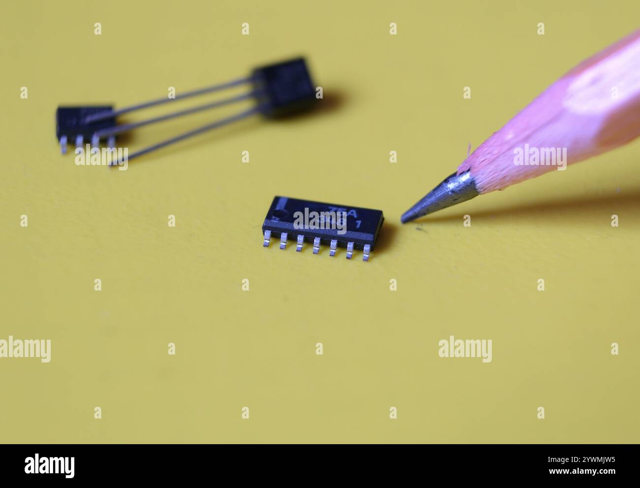 Halbleiter-IC oder integrierte Schaltung und ein Bleistift auf gelbem Hintergrund. Stockfoto