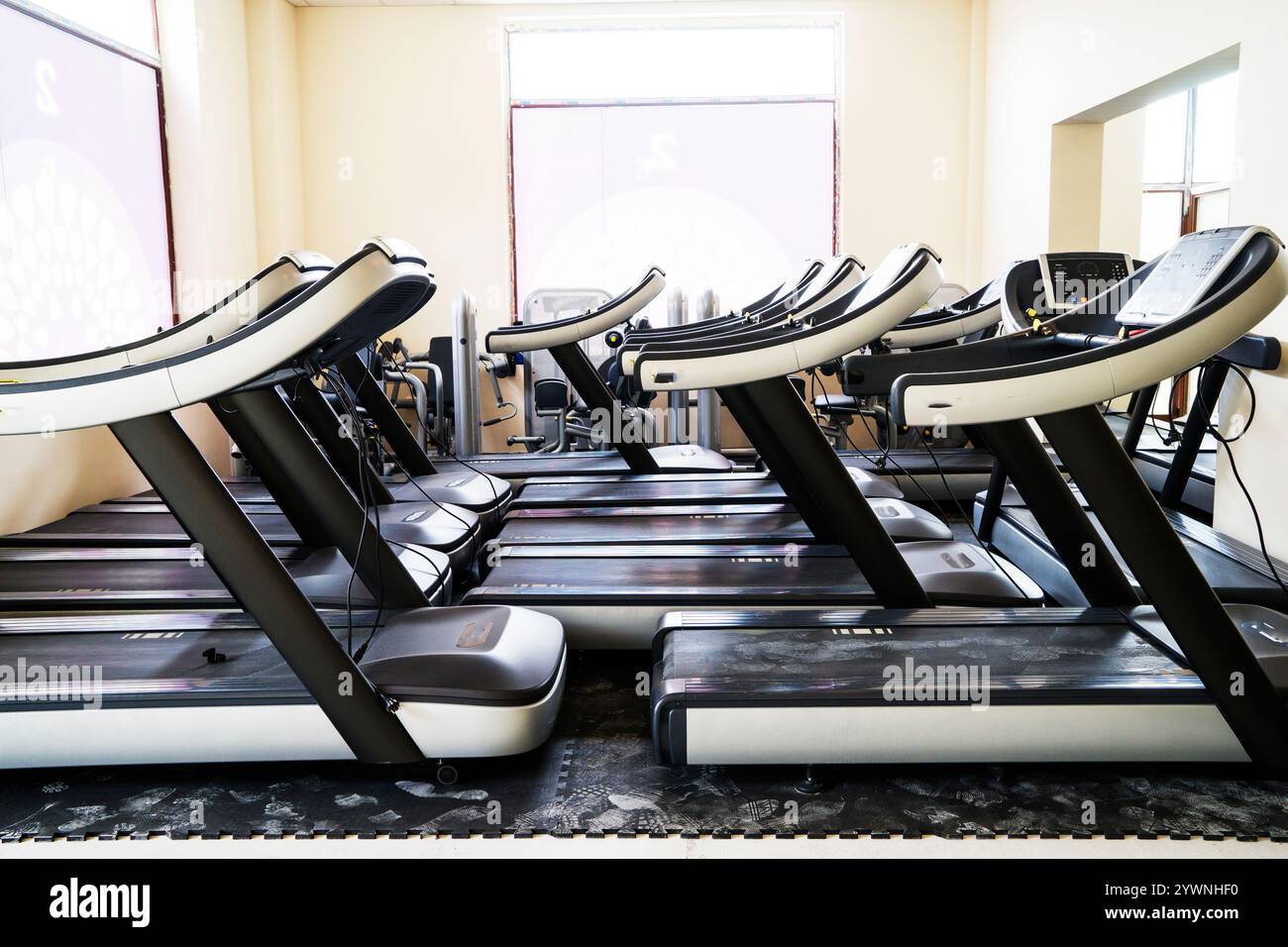 Moderne Innenausstattung des Fitnessstudios mit Geräten. Fitnessclub mit Laufbändern für Fitness-Cardio-Training bei abendlicher Beleuchtung. Gesundes Lifestyle-Konzept Stockfoto